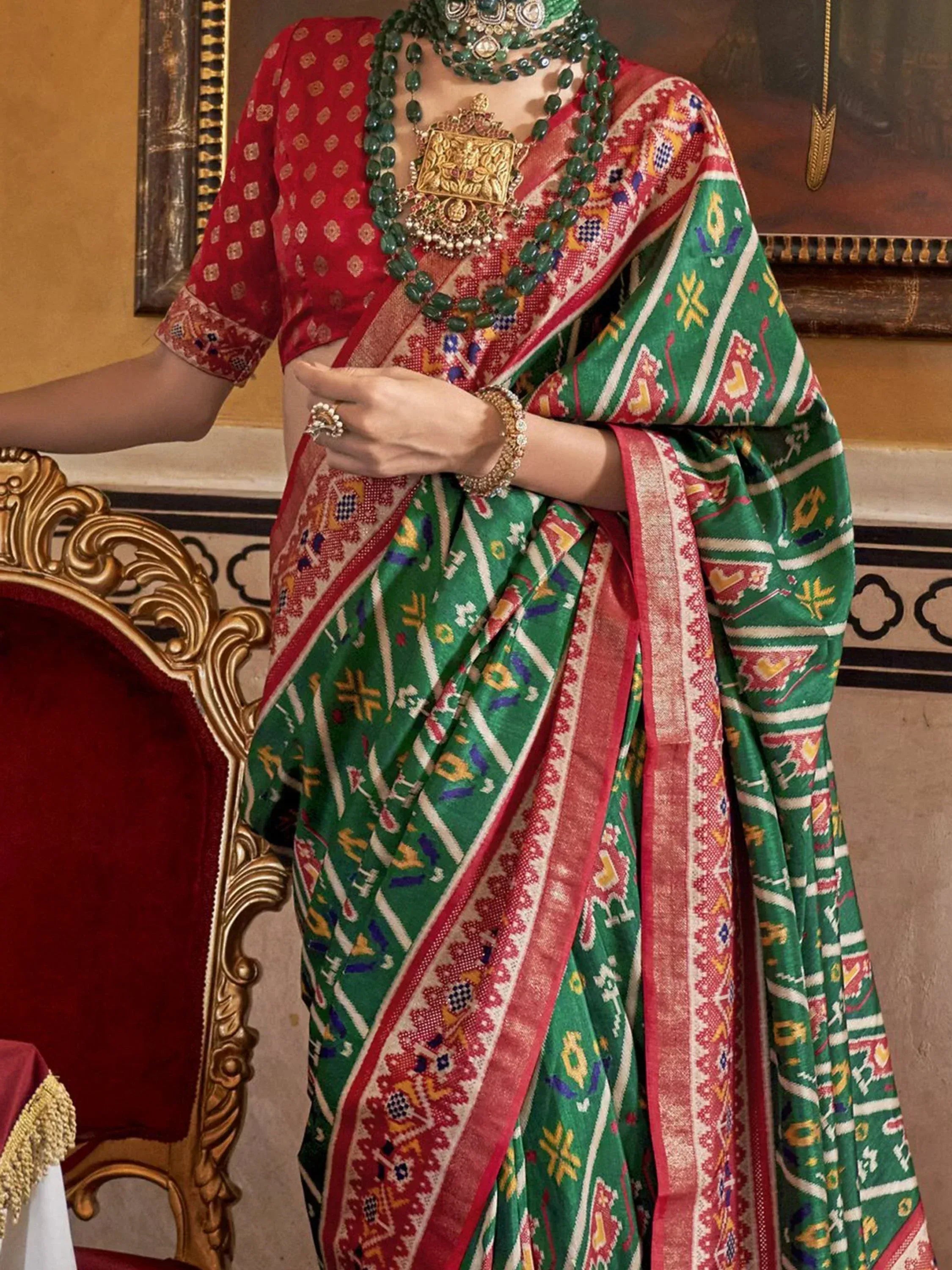 Green and red ethnic saree with intricate patterns, paired with traditional jewelry and blouse, perfect for Indian occasions.