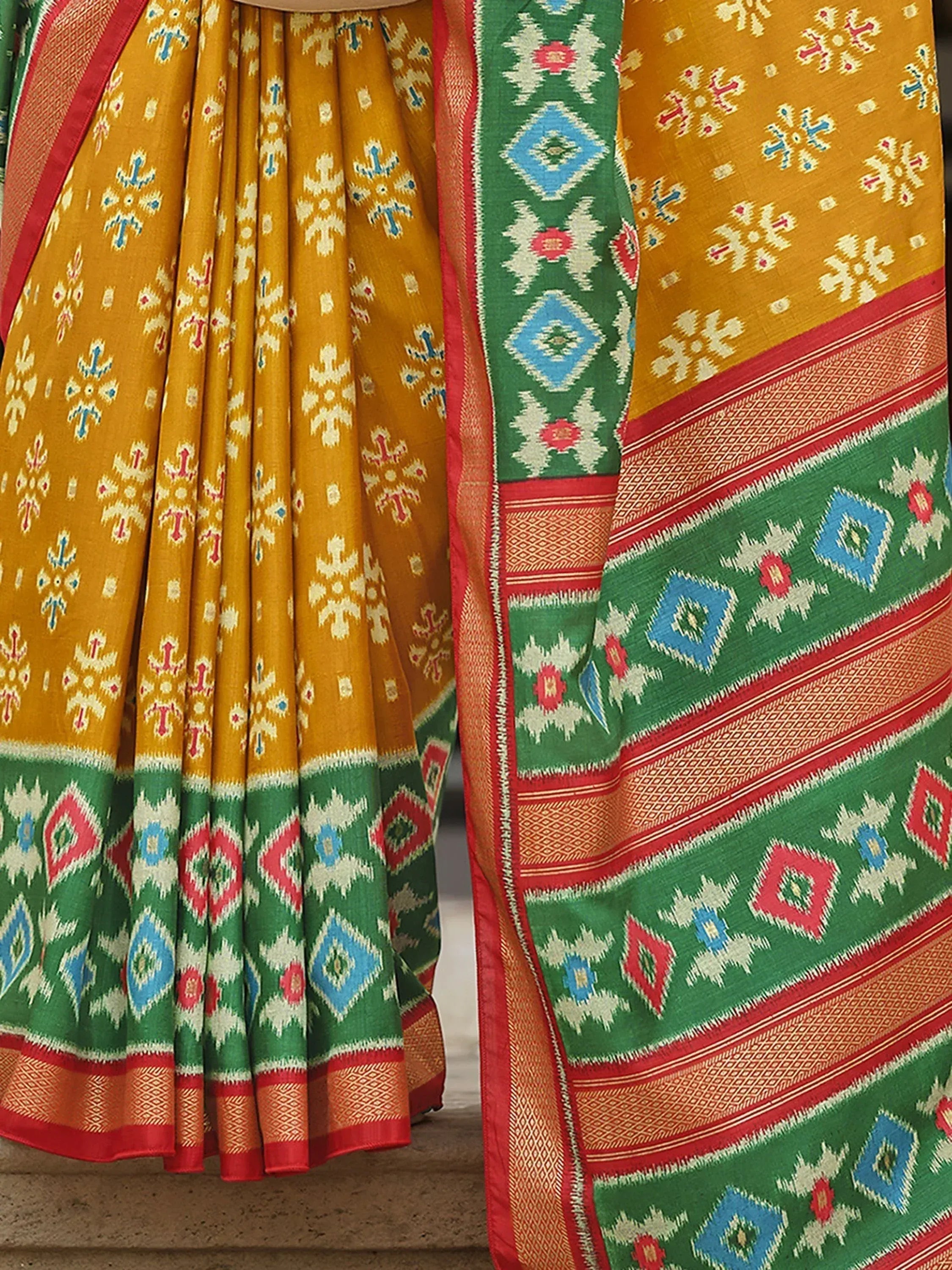 Vibrant yellow and green ethnic saree with geometric ikat patterns and red border, perfect for Indian occasions