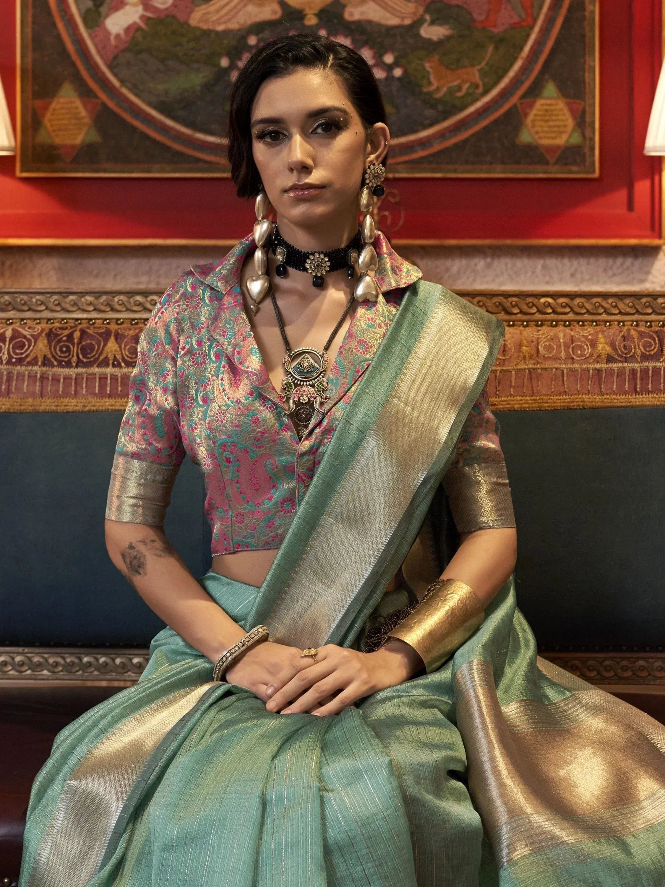Woman in mint green saree with gold border and floral blouse, styled with traditional Indian jewelry