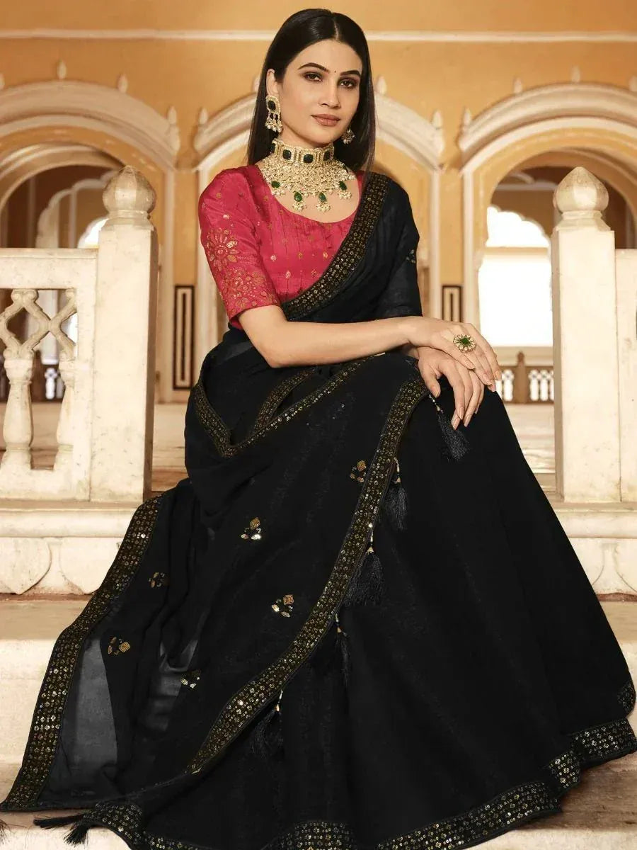 Black embroidered saree with pink blouse, gold trim, and green jewelry for Indian ethnic wear