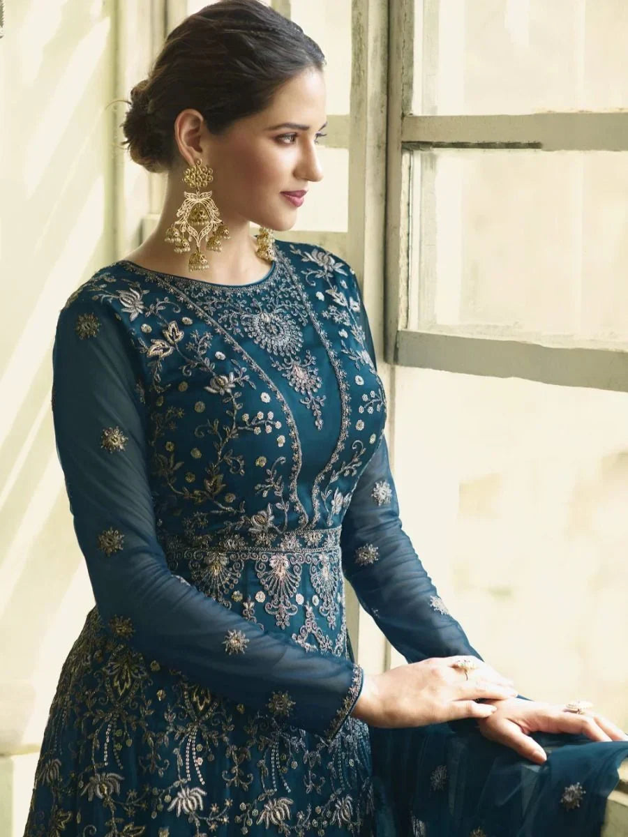 Woman in a navy blue embroidered ethnic gown with sheer sleeves and gold jhumka earrings