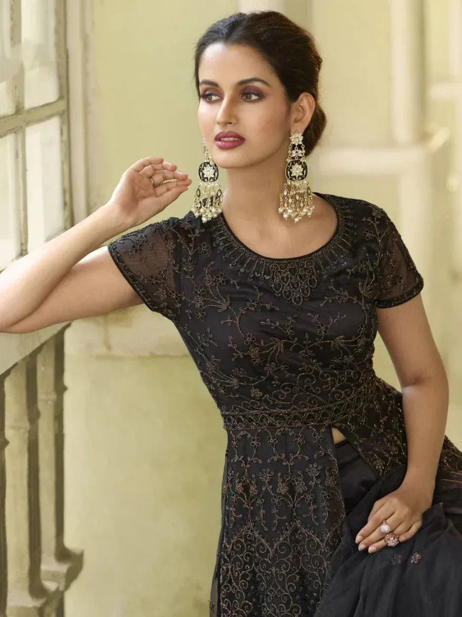 Black embroidered ethnic gown with sheer sleeves and gold detailing, paired with statement earrings