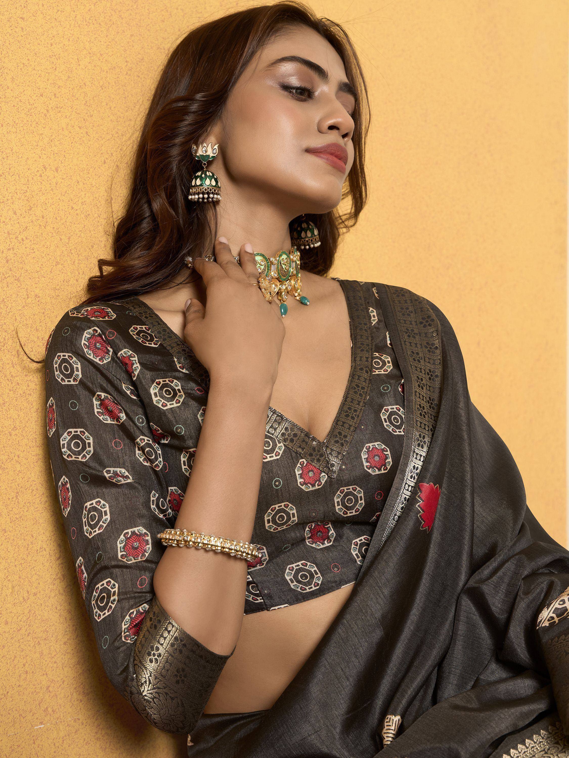Woman in black printed saree with gold embroidery, wearing traditional Indian jewelry, perfect for ethnic occasions.