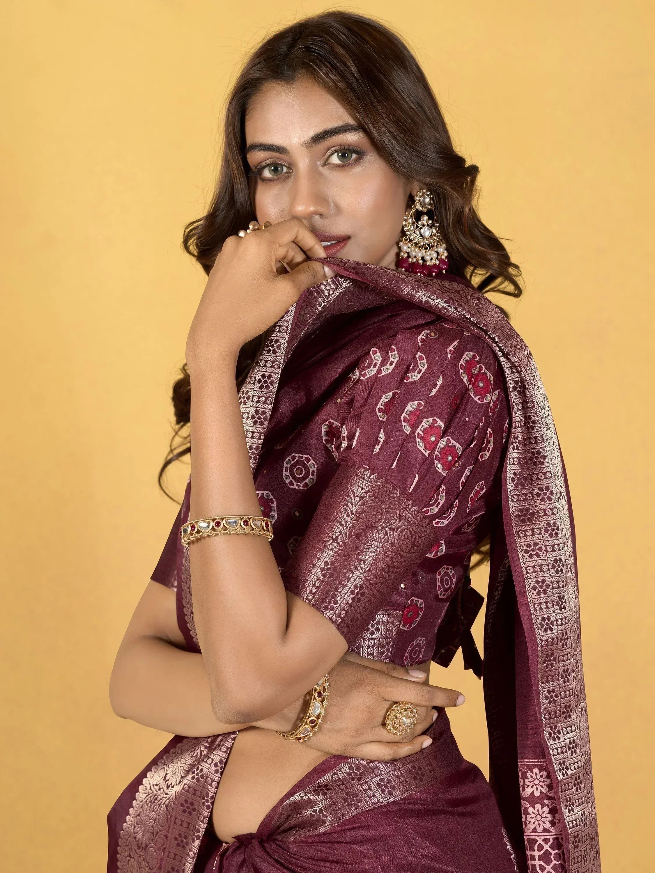 Woman in maroon ethnic saree with gold embroidery and traditional jewelry, perfect for Indian occasions