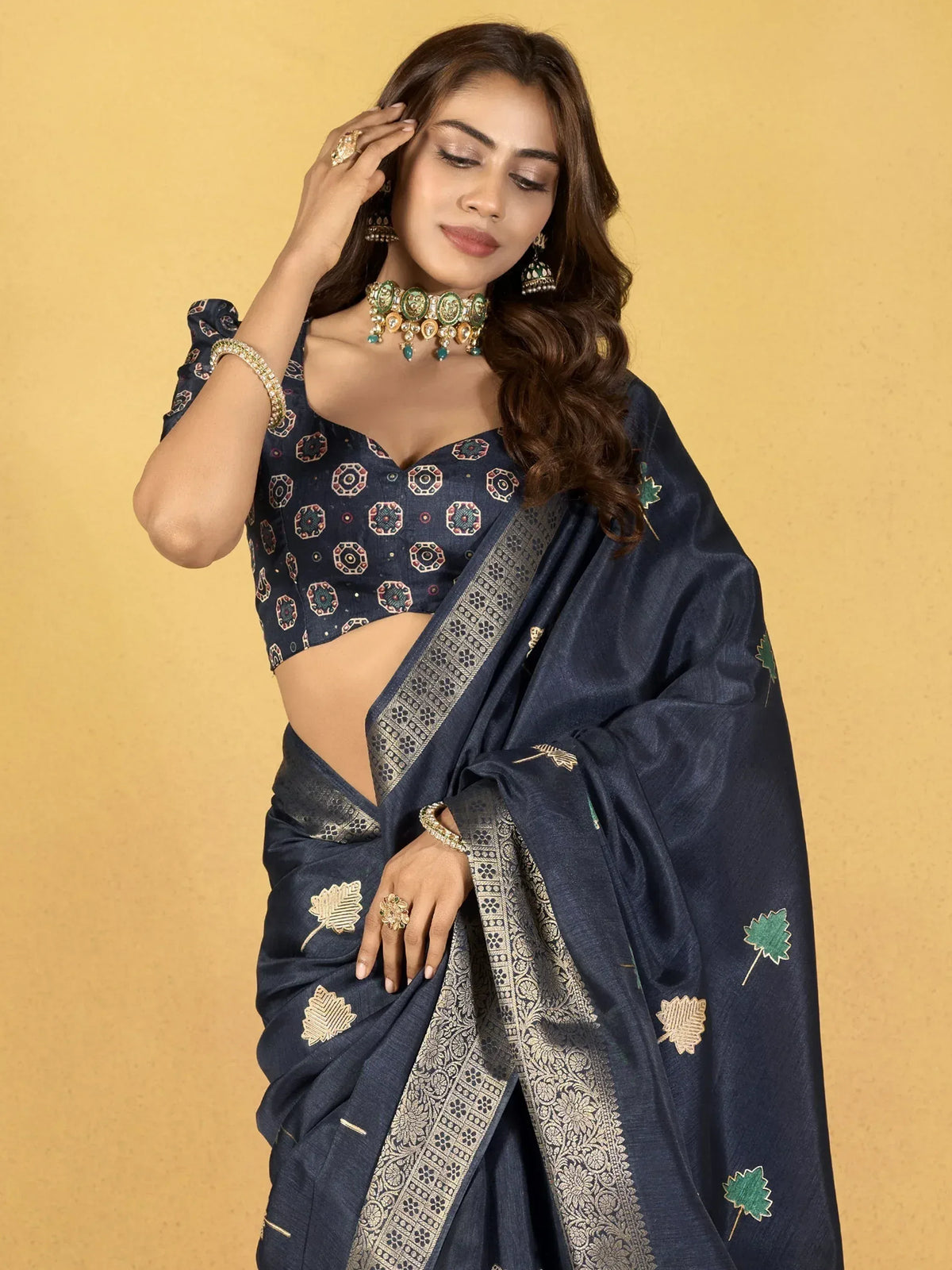 Navy blue ethnic saree with leaf embroidery and gold border, paired with printed blouse and traditional jewelry