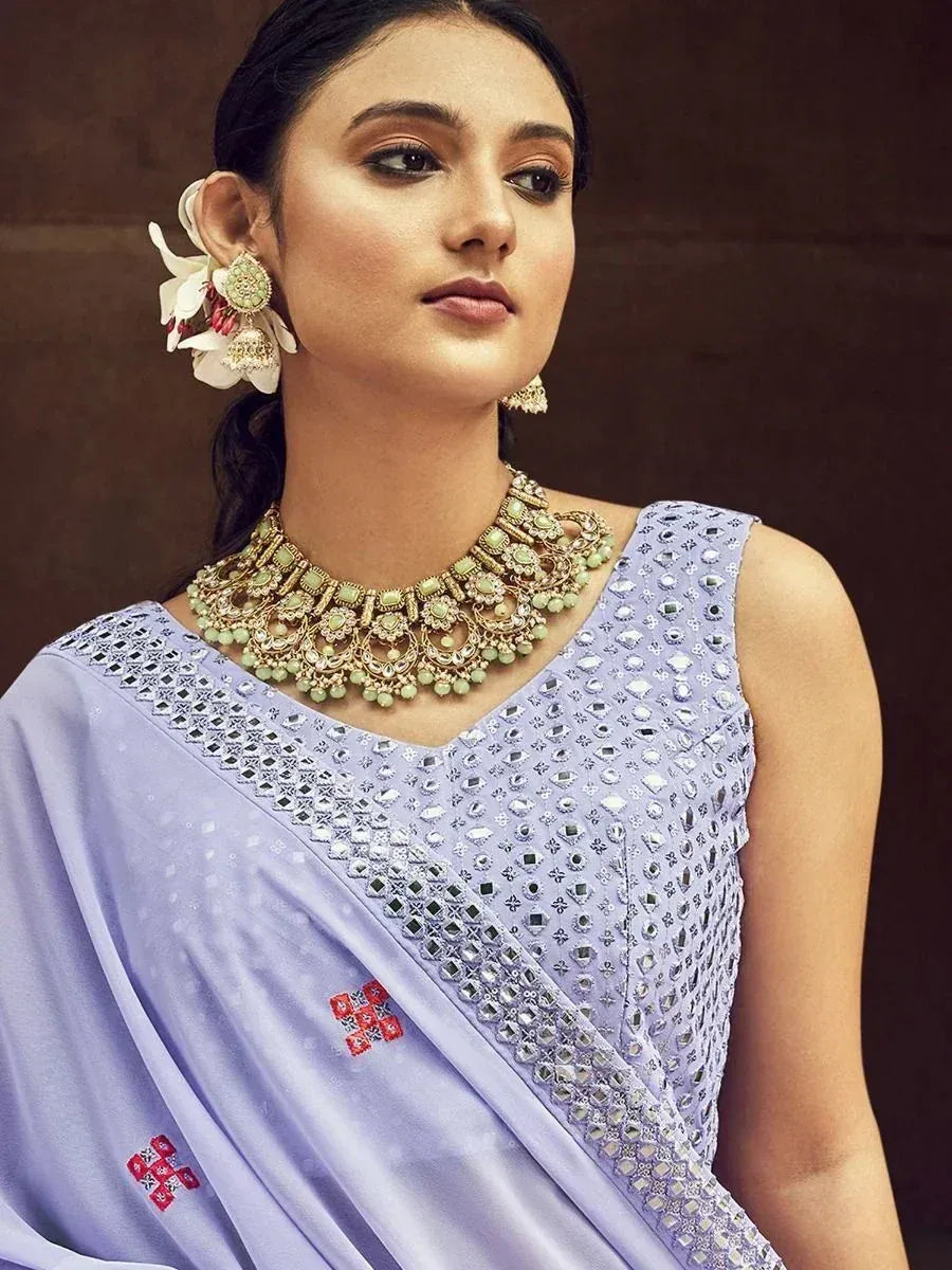 Woman in lavender ethnic saree with mirror work, floral hair accessory, and statement jewelry