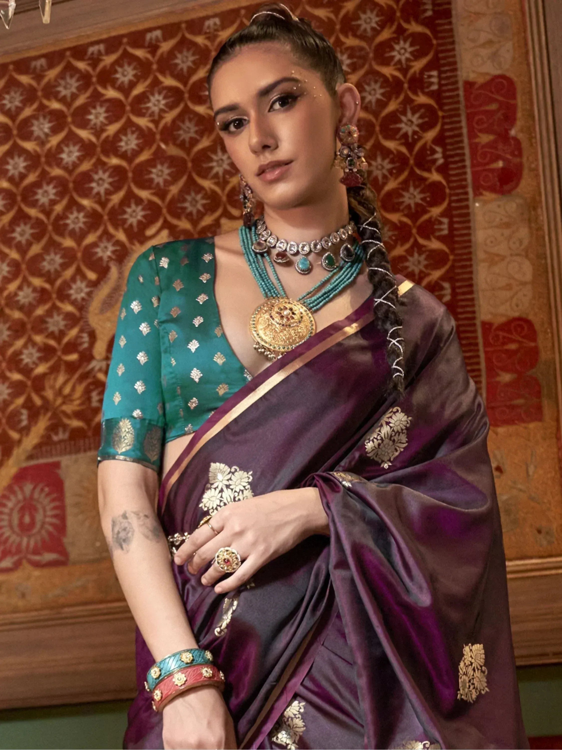 Elegant purple saree with gold embroidery, paired with a teal blouse and traditional jewelry.