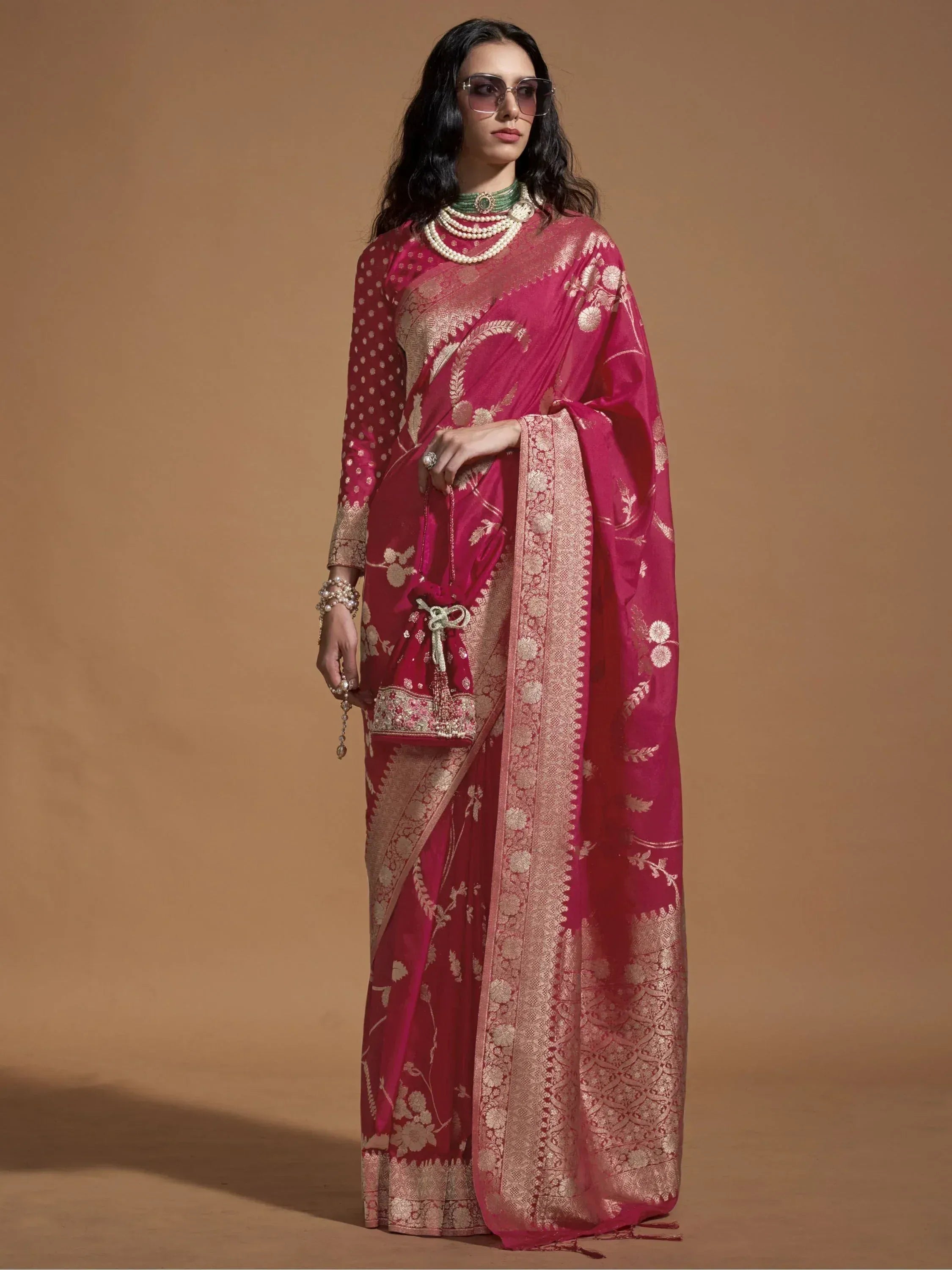 Elegant pink designer saree with gold floral embroidery and border, paired with matching blouse and pearl jewelry