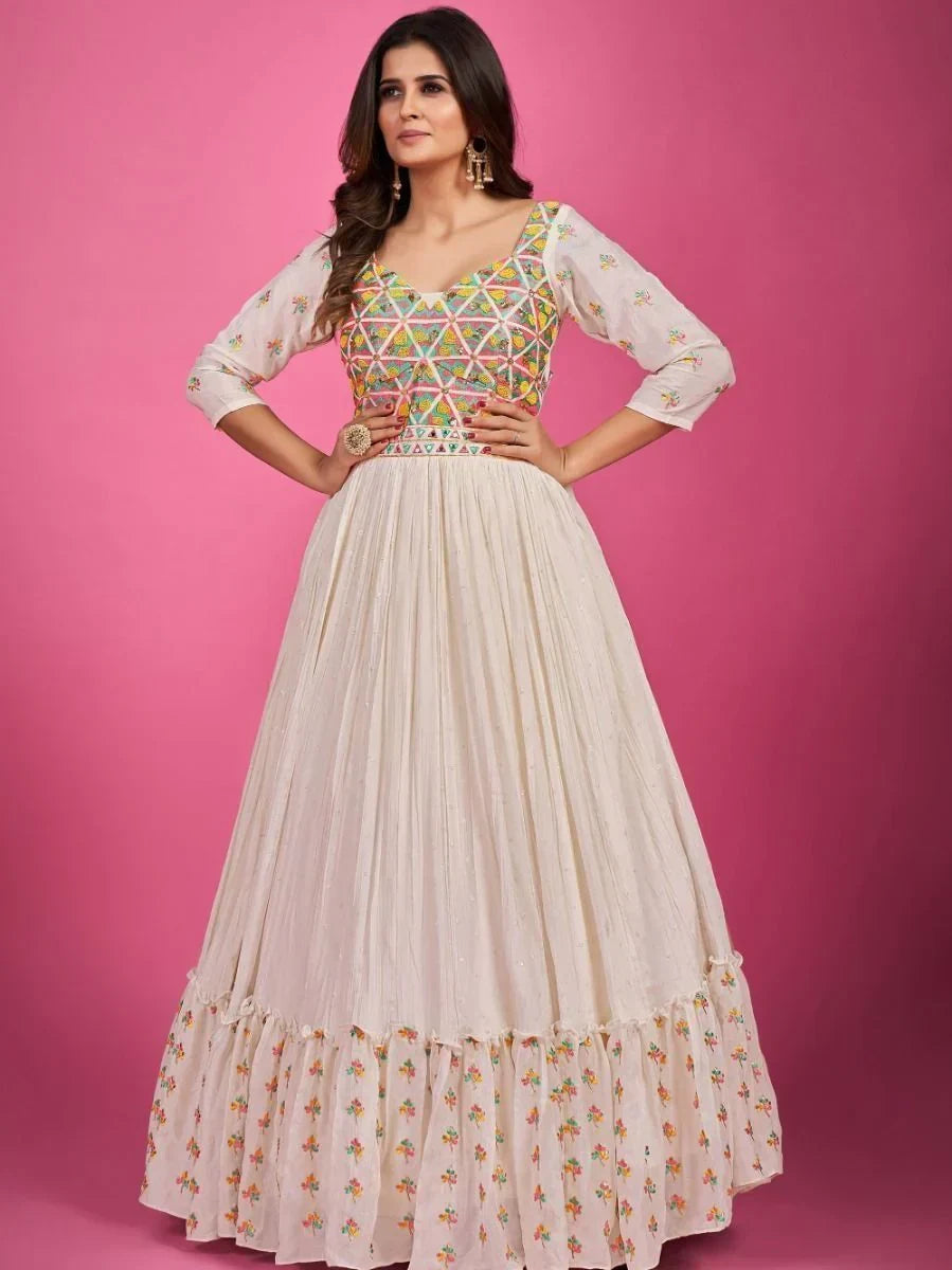 Woman in cream ethnic gown with colorful embroidered bodice and sleeves, pink background