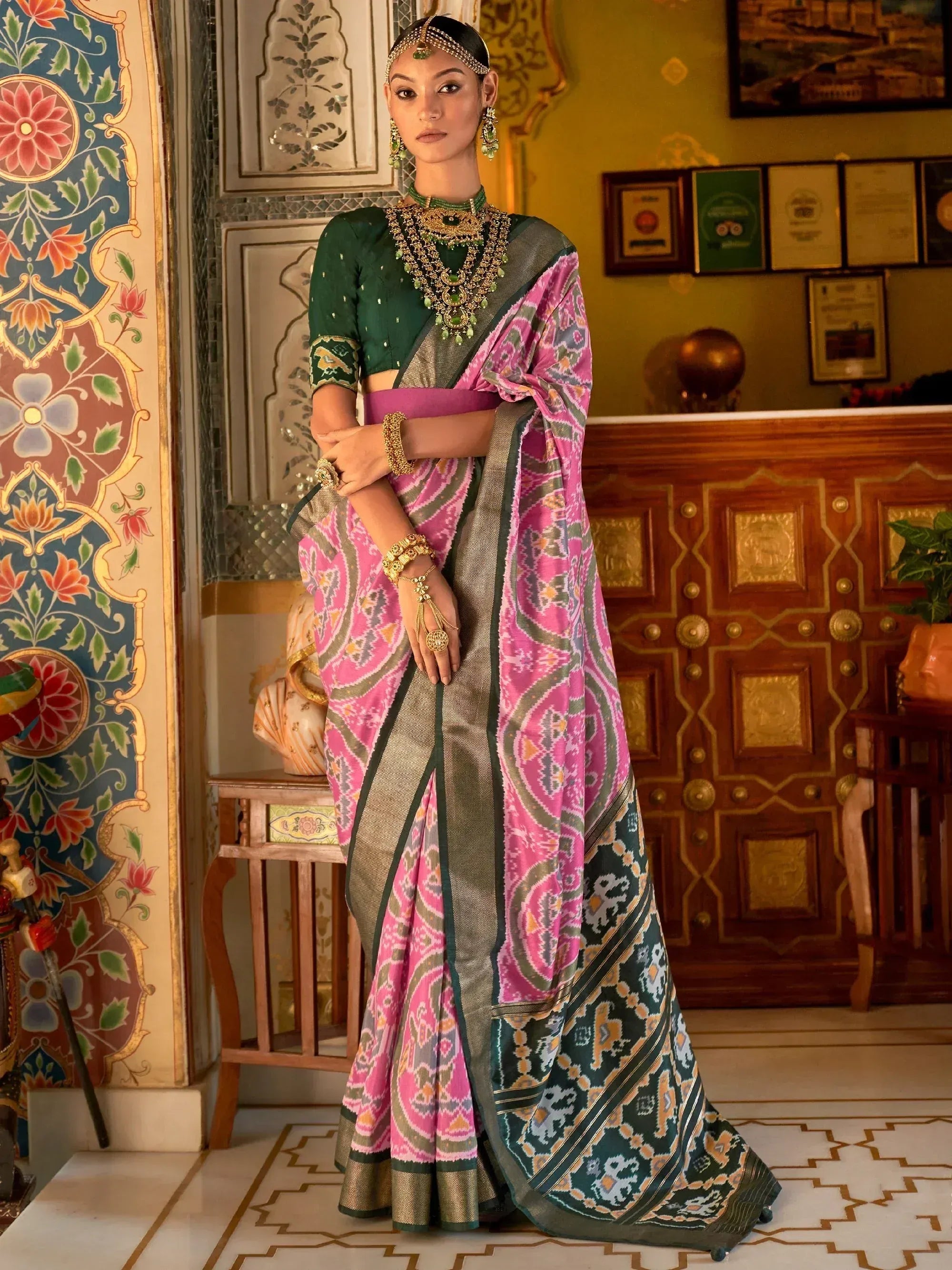 Elegant woman in designer pink and green saree with gold jewelry, showcasing ethnic wear.