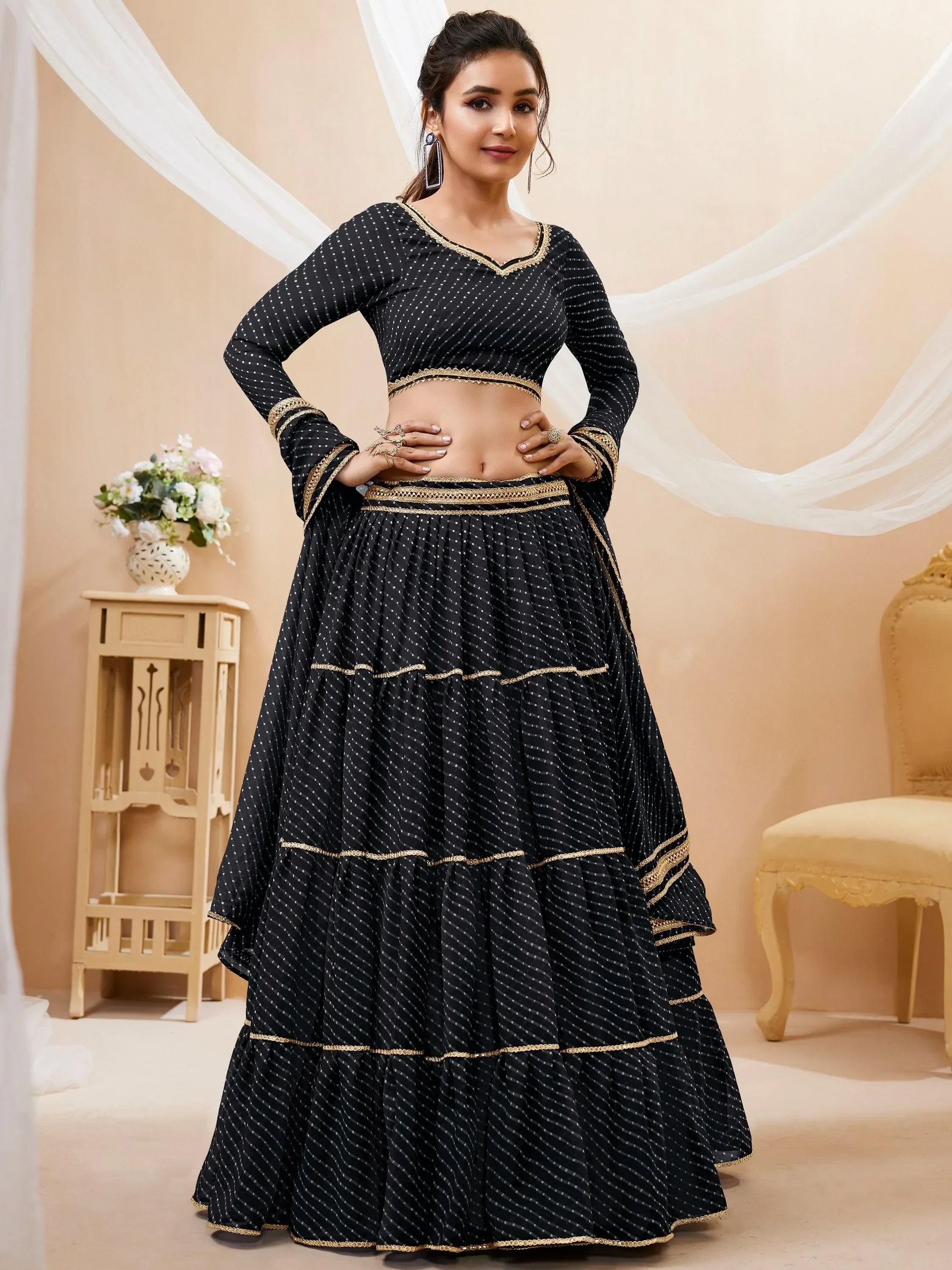 Black and gold polka dot lehenga choli with tiered skirt and embroidered borders, perfect for Indian ethnic occasions.