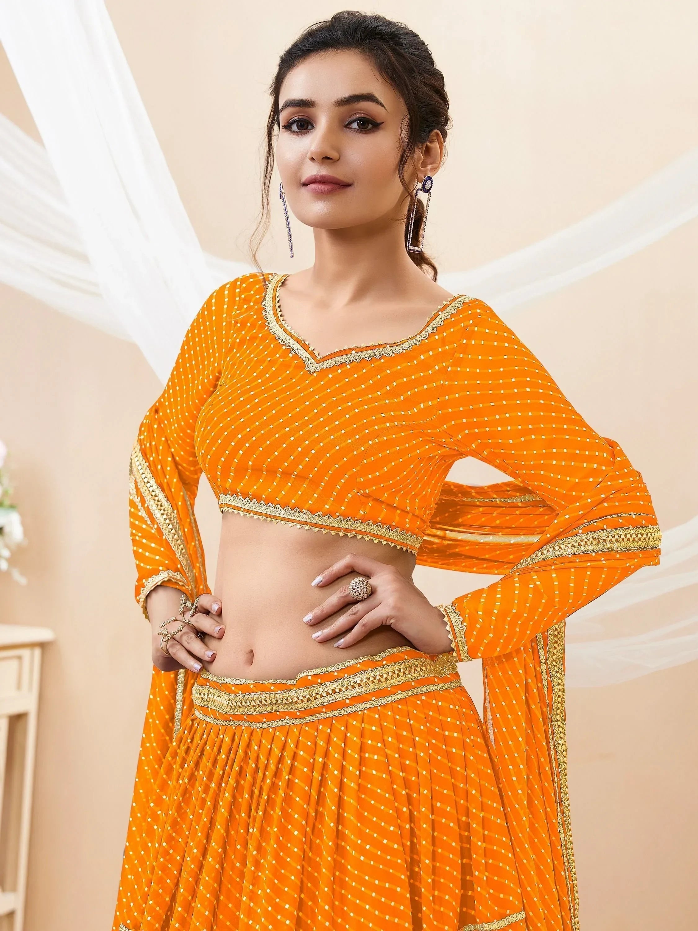 Vibrant orange ethnic lehenga choli with gold embroidery and mirror work, perfect for festive occasions
