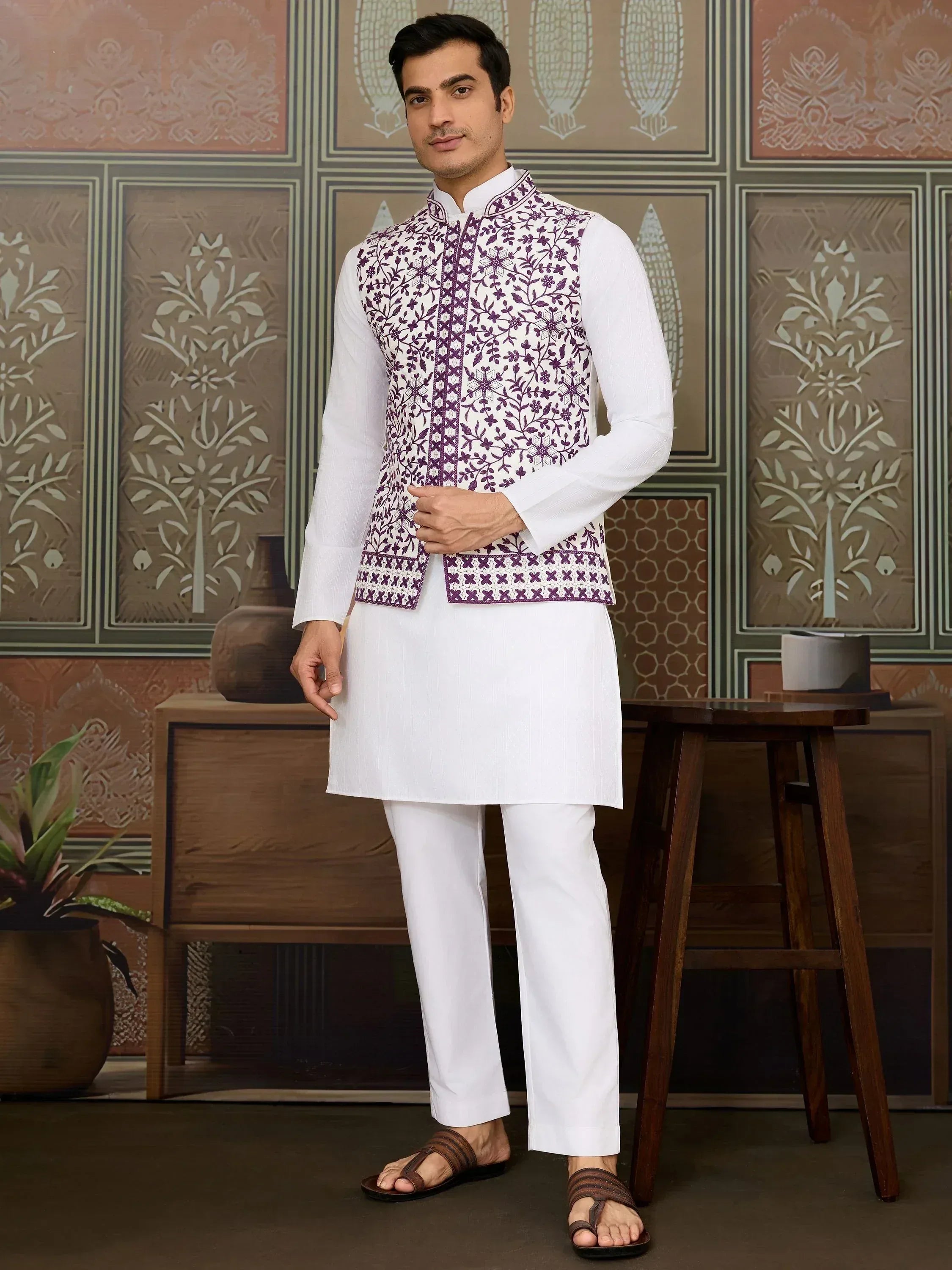 Man in white kurta pajama with purple floral embroidered vest, ethnic Indian wear