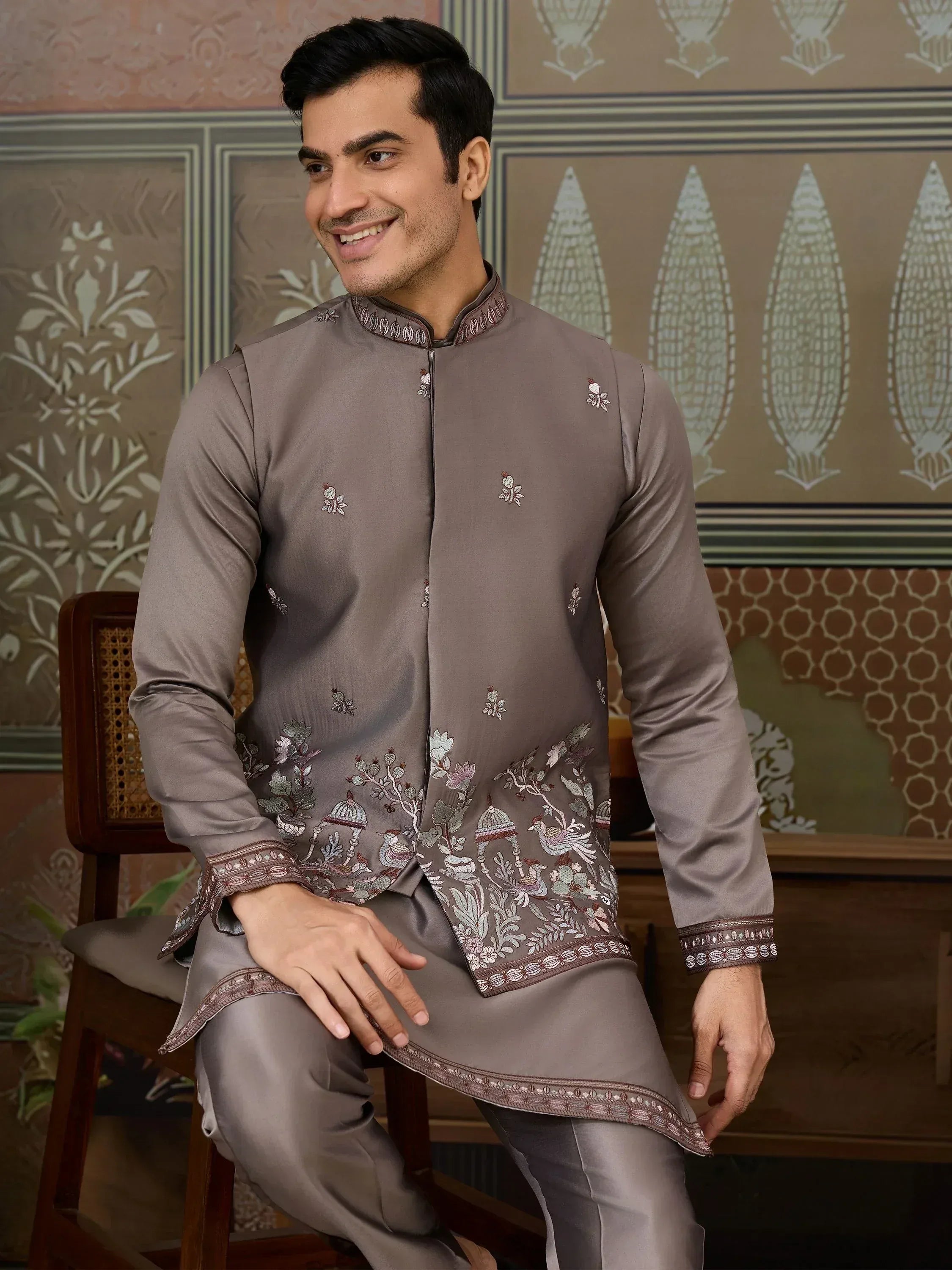Man wearing grey embroidered kurta pajama set with floral and bird motifs, ideal for Indian ethnic occasions.