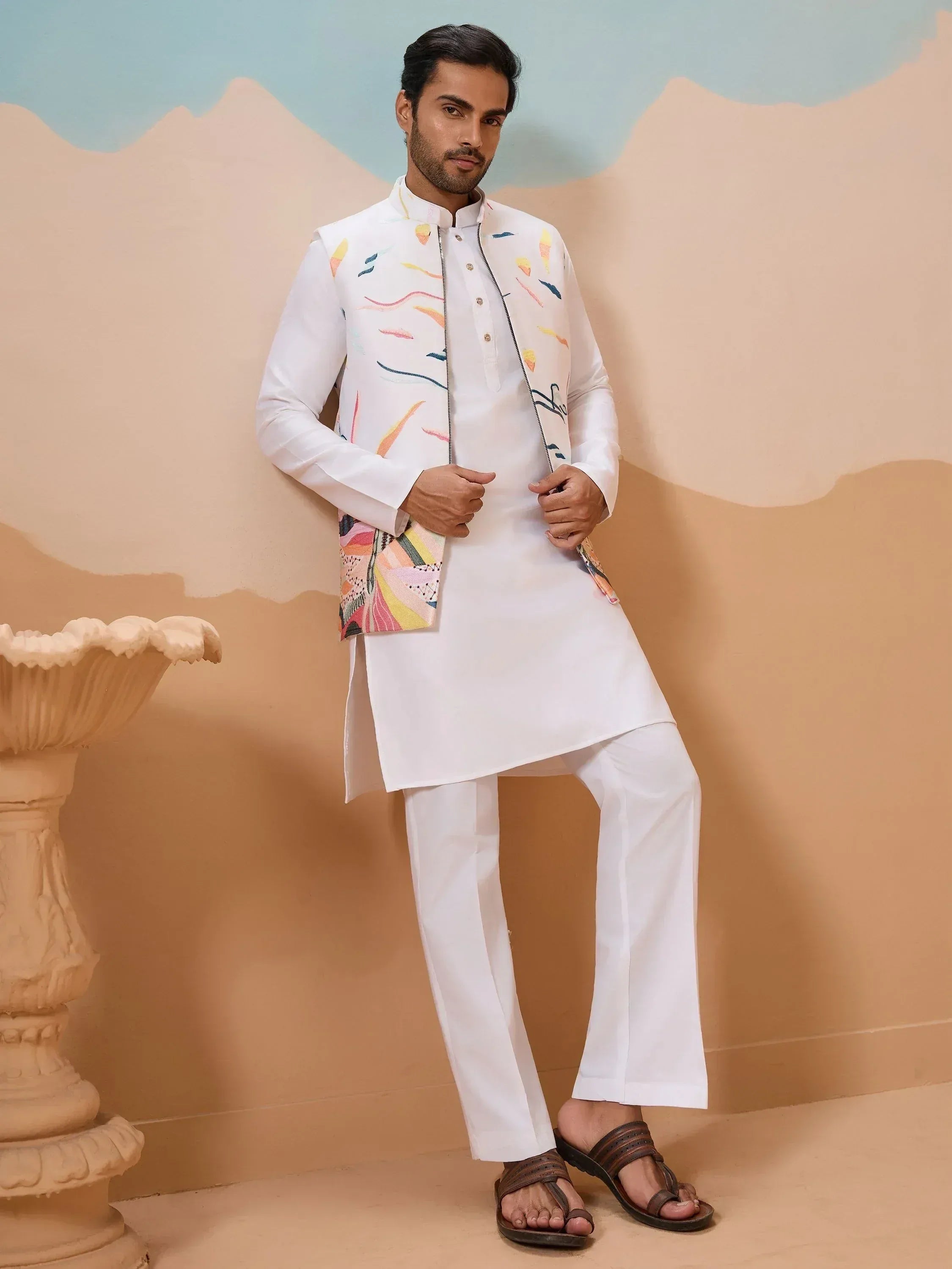 Man in white kurta set with colorful embroidered vest, ethnic wear for men