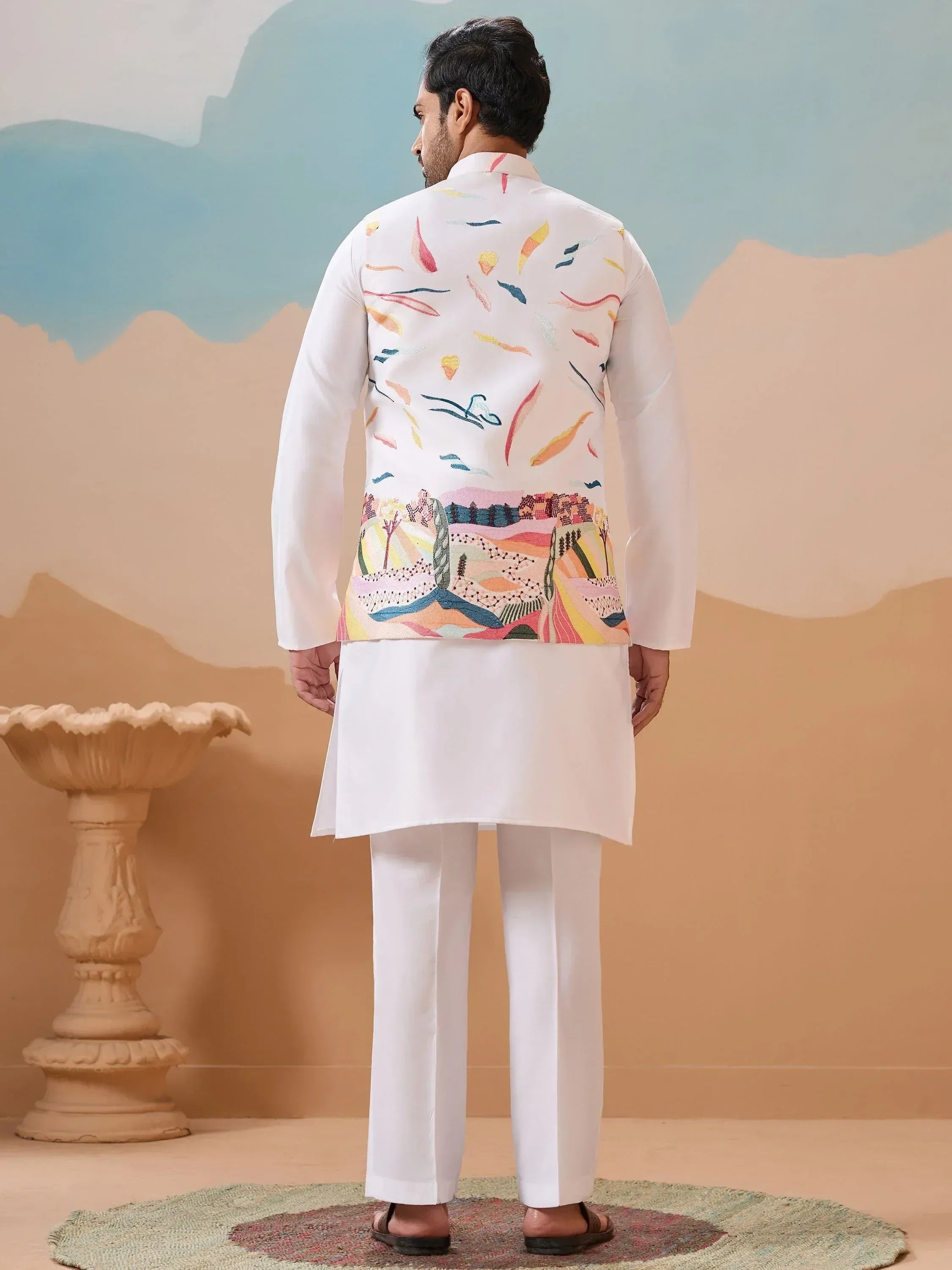 Man in white kurta pajama with colorful embroidered jacket, ethnic Indian wear