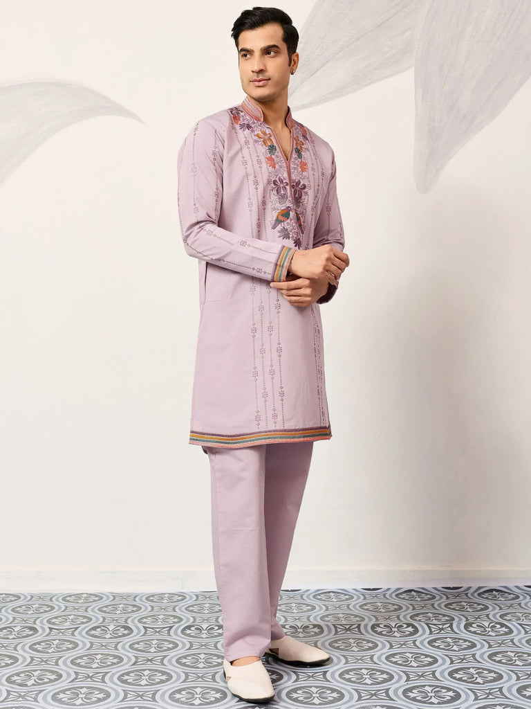 Men's lavender kurta set with floral embroidery and colorful trim, paired with matching pants.