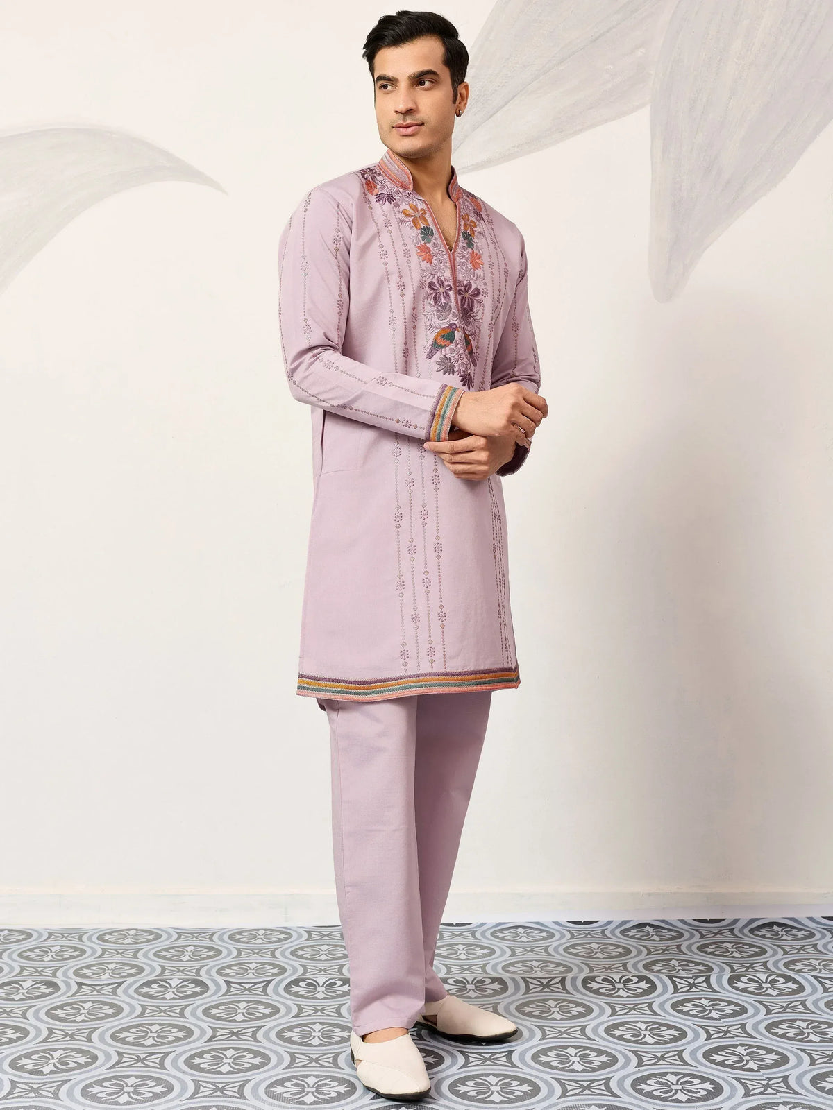 Men's lavender kurta set with floral embroidery and colorful trim, paired with matching pants.