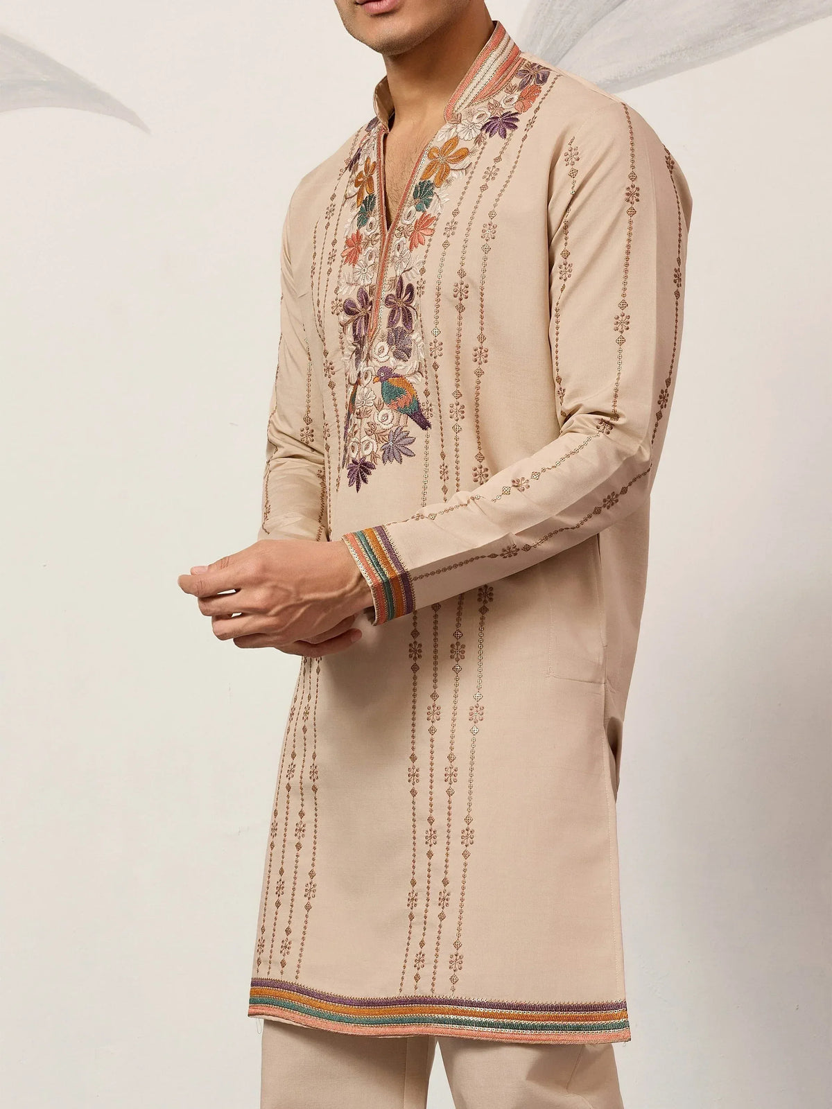 Beige embroidered kurta with floral and bird motifs, colorful striped cuffs and hem, ethnic wear for men