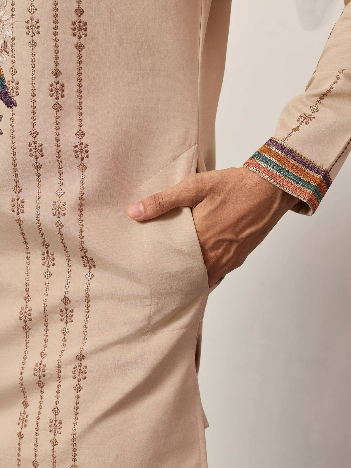 Beige ethnic kurta with gold embroidery and colorful striped cuffs, hand in pocket detail