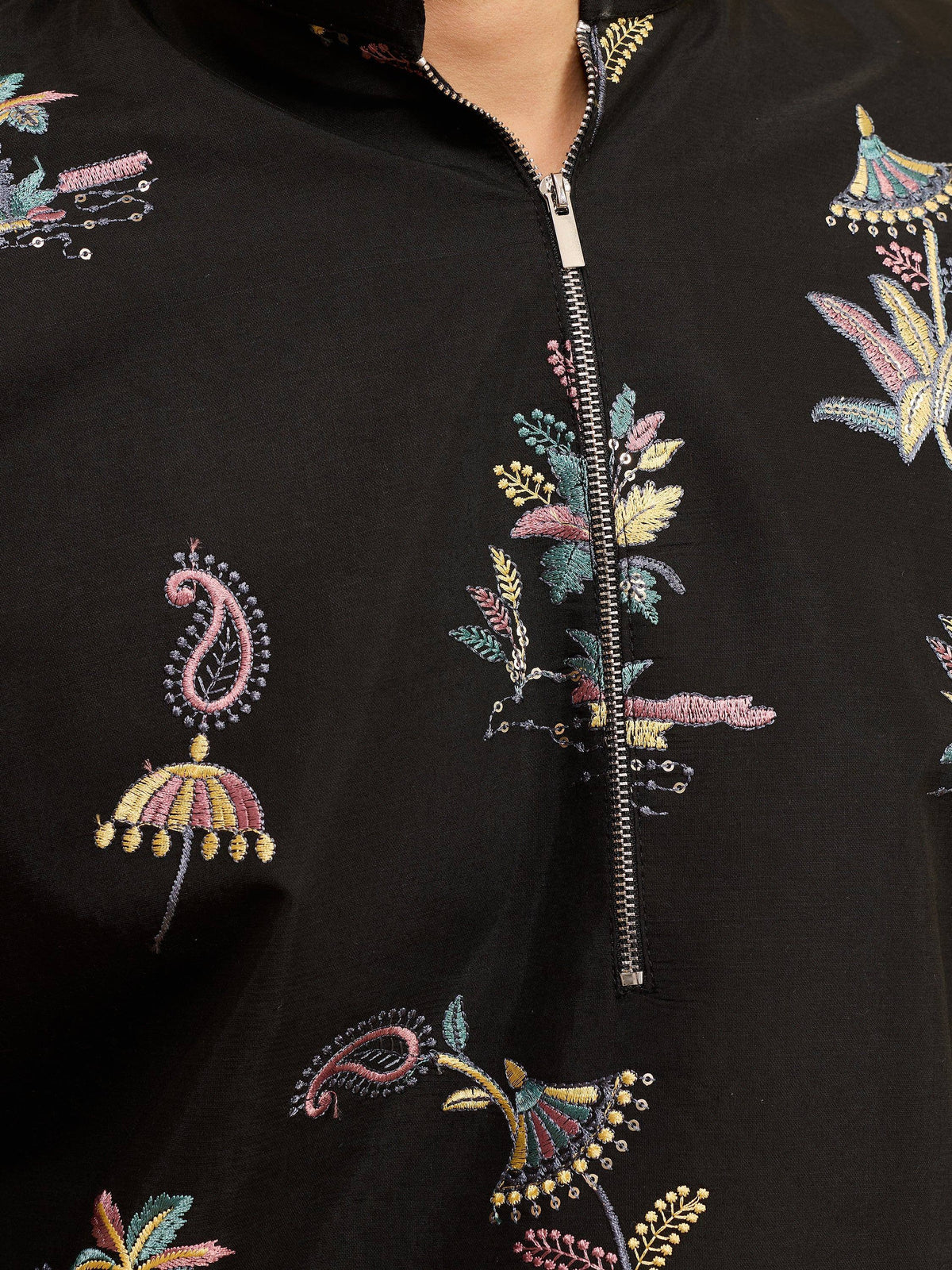 Close-up of a black ethnic garment featuring colorful floral and paisley embroidery with a zipper.