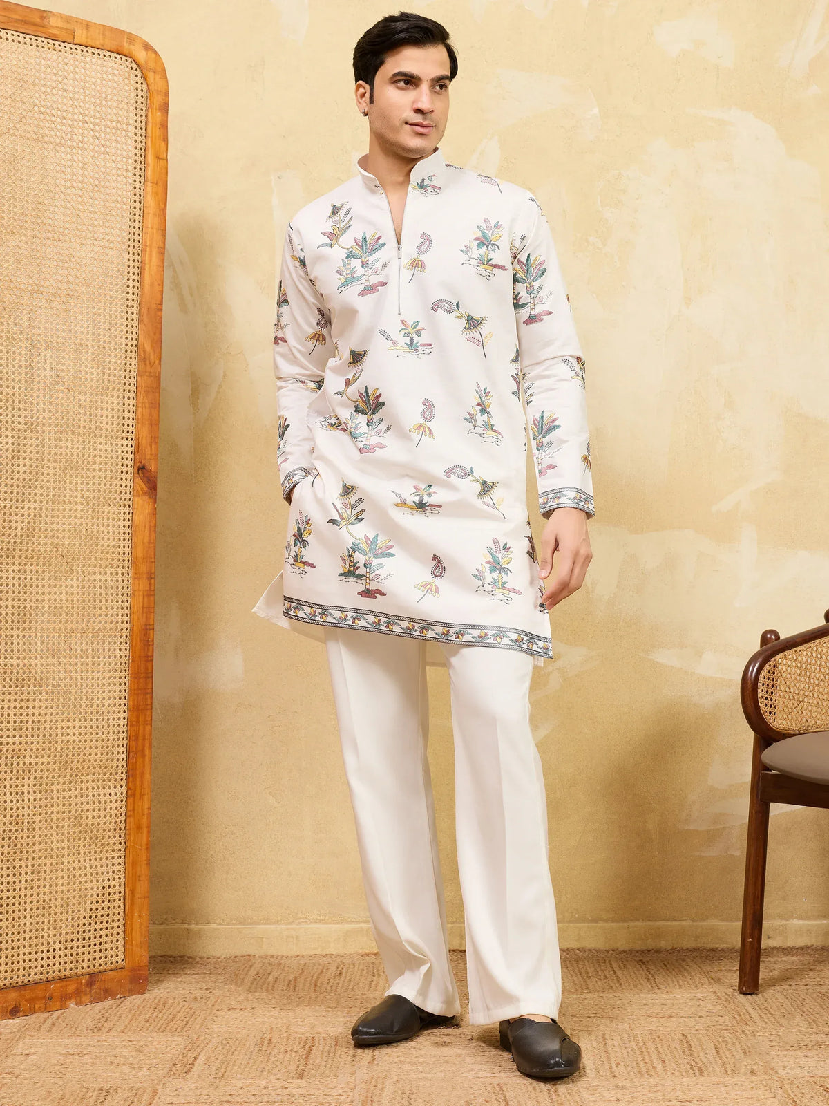 Man wearing a white floral printed ethnic kurta with white trousers and black loafers.