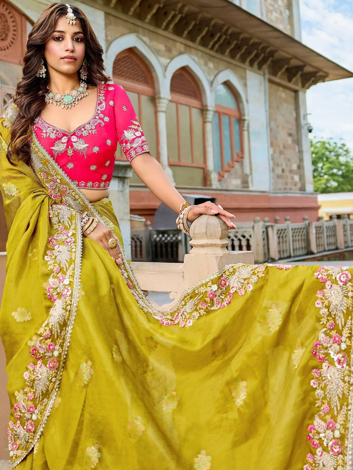 Woman in vibrant yellow embroidered saree with pink blouse, traditional Indian ethnic wear