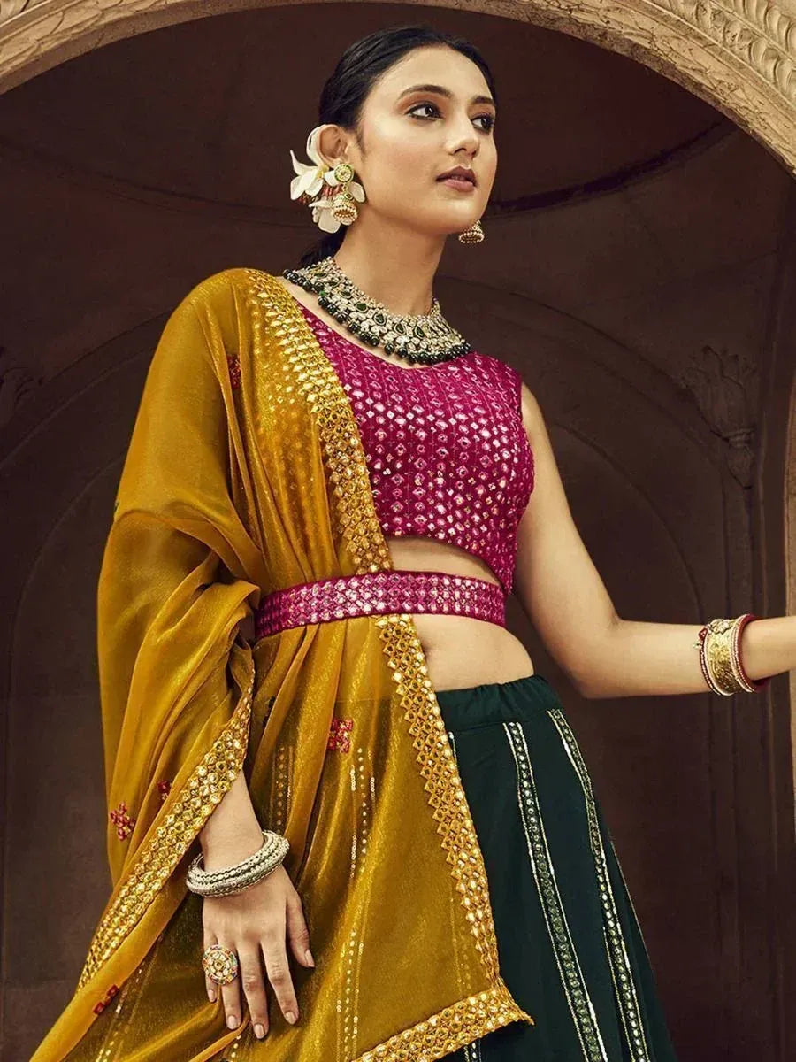 Elegant Indian lehenga choli with pink embellished blouse, gold dupatta, and green skirt, styled with traditional jewelry.