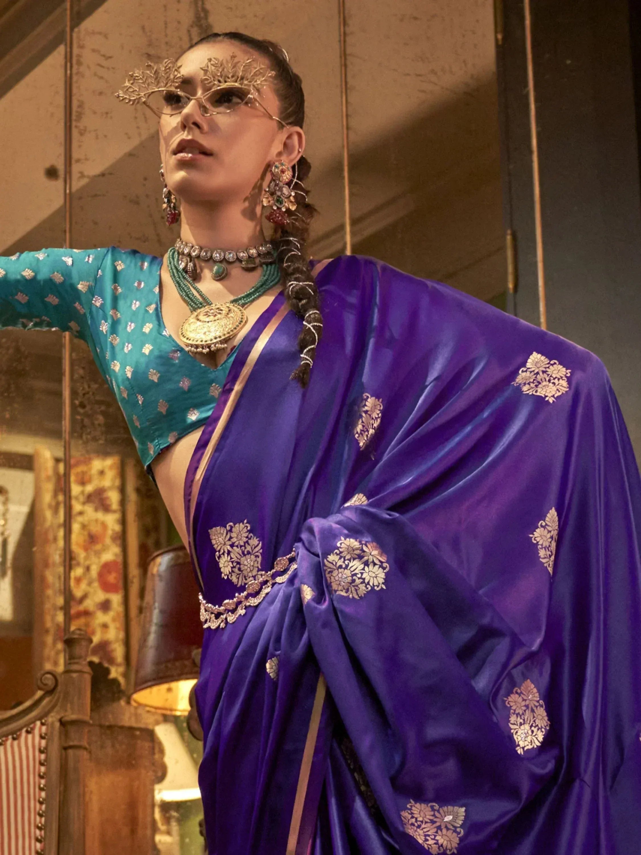 Purple saree with gold floral embroidery, paired with teal blouse and traditional jewelry