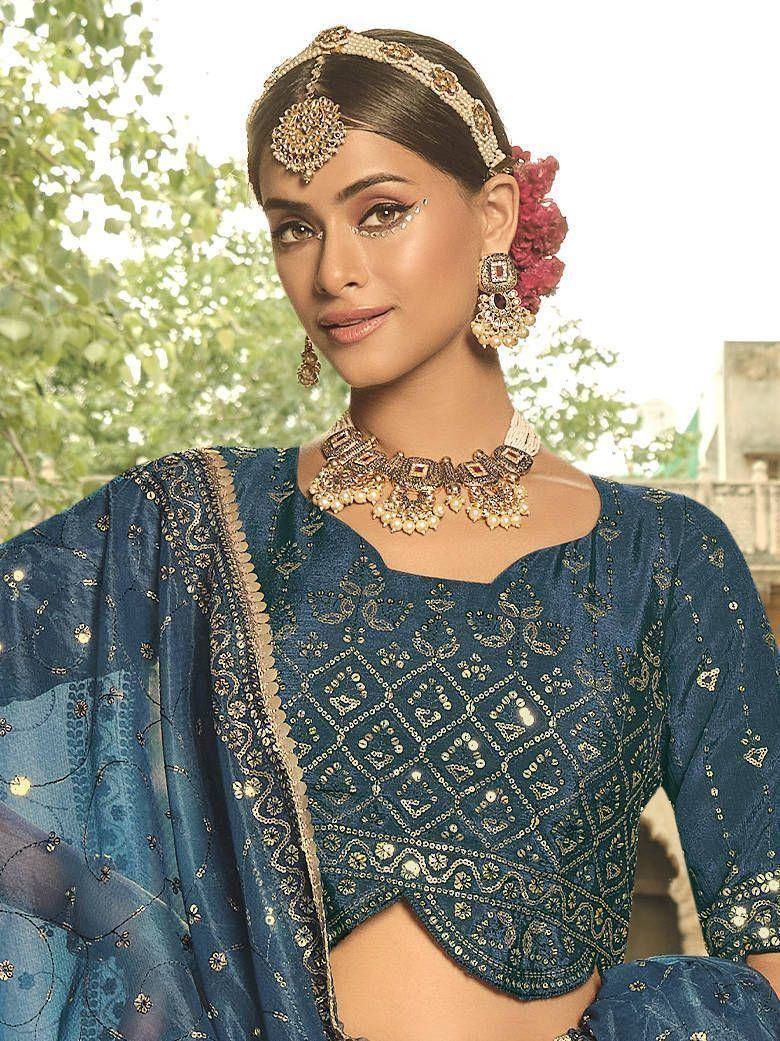 Blue embroidered Indian ethnic blouse with gold detailing, paired with traditional jewelry and floral hair accessory