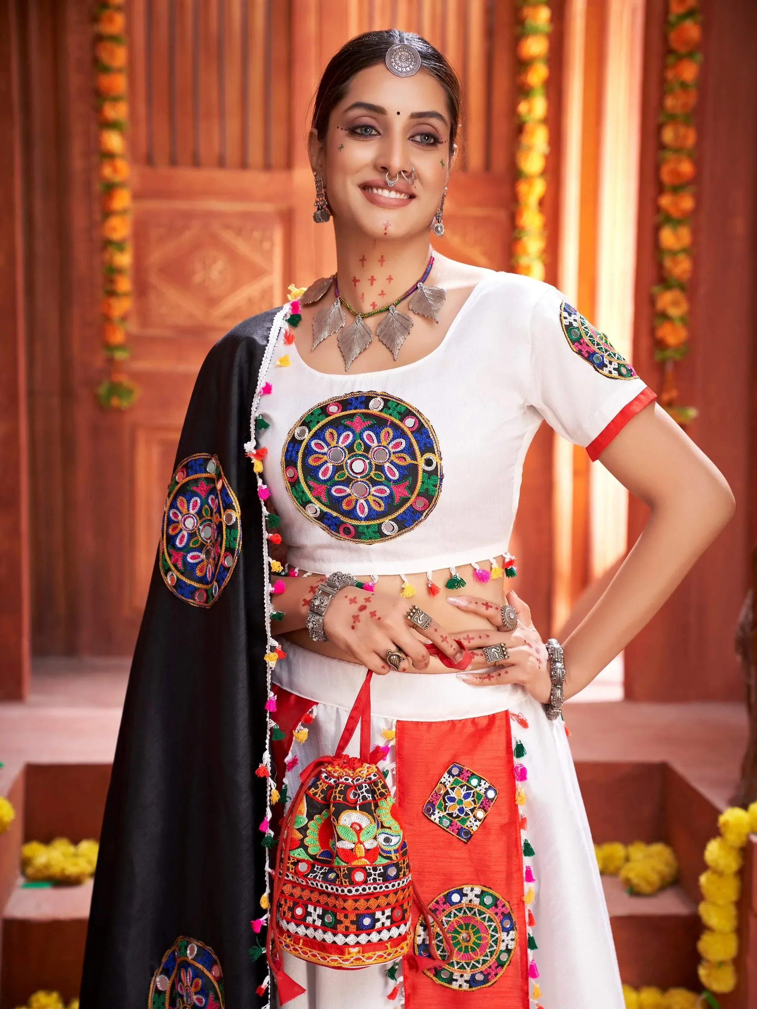 Woman in white embroidered choli with mirror work, red and black dupatta, traditional Indian ethnic wear
