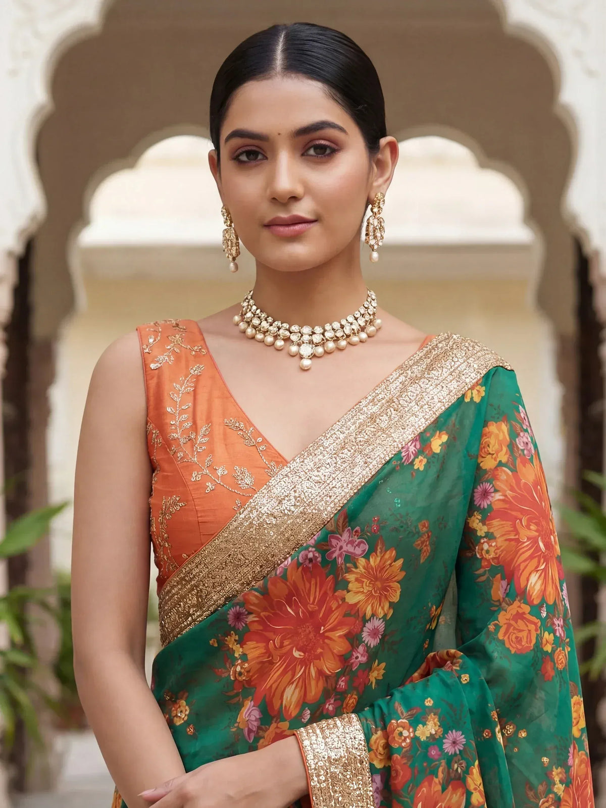 Woman in green floral saree with orange embroidered blouse, gold jewelry, traditional Indian ethnic wear