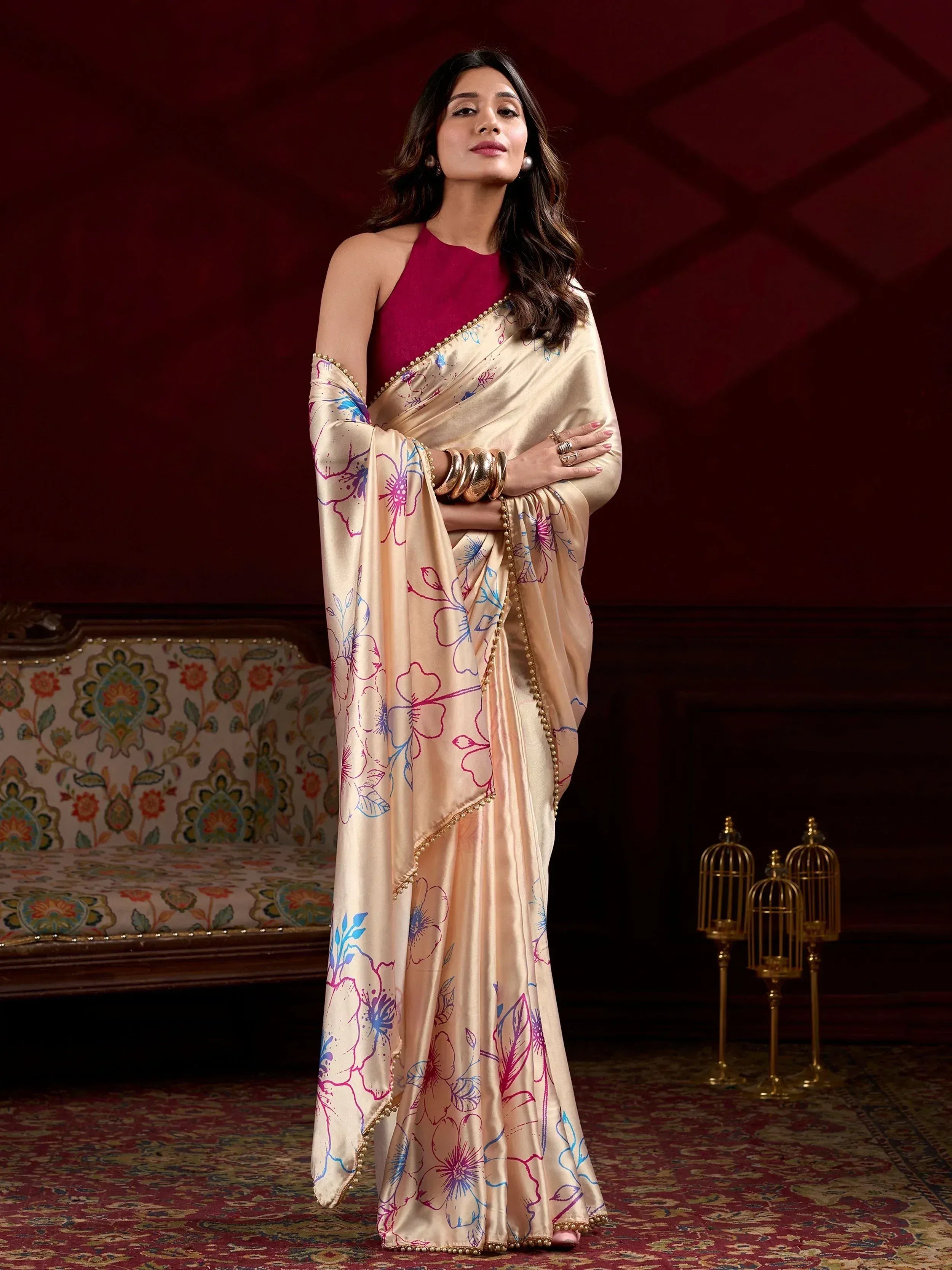 Elegant cream saree with floral print and gold border, paired with maroon halter blouse, perfect for Indian ethnic occasions.