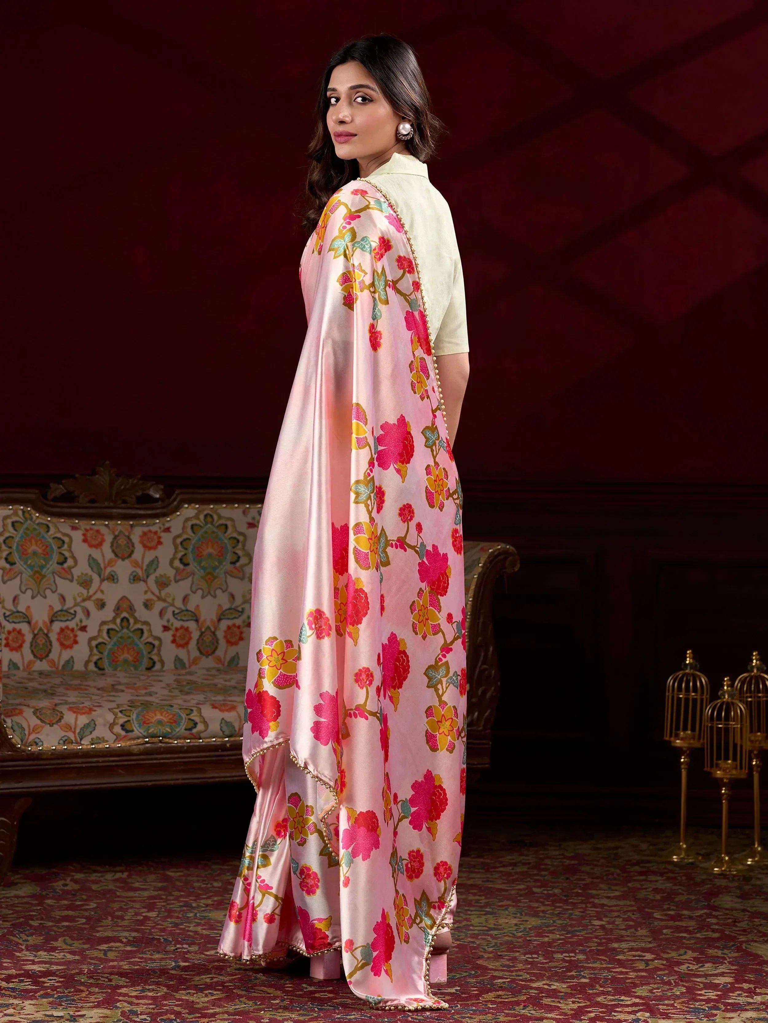 Pink floral printed Indian ethnic gown with gold trim, styled with pearl earrings for festive occasions