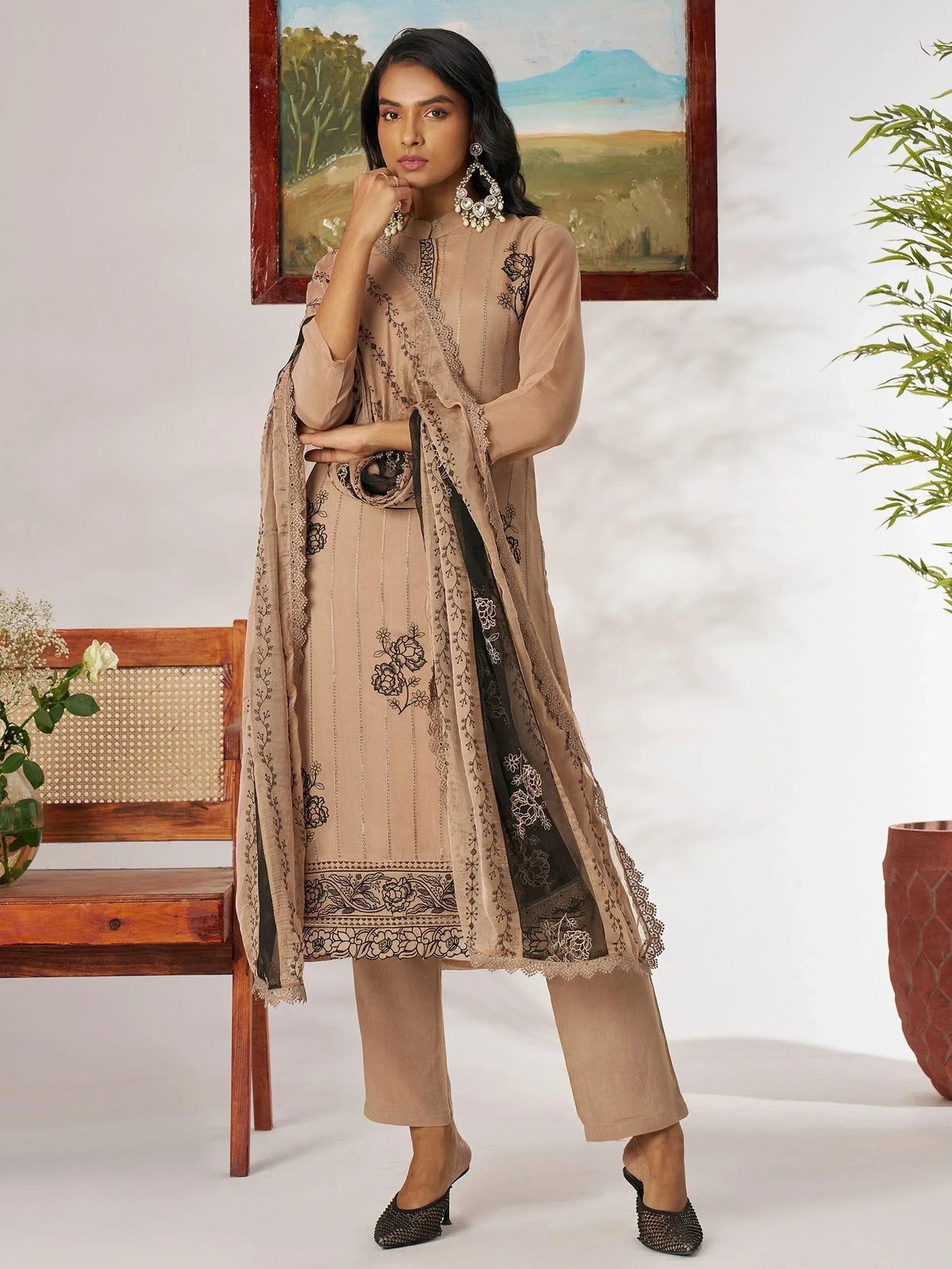 Beige embroidered salwar kameez with black floral detailing and lace dupatta, styled with statement earrings.
