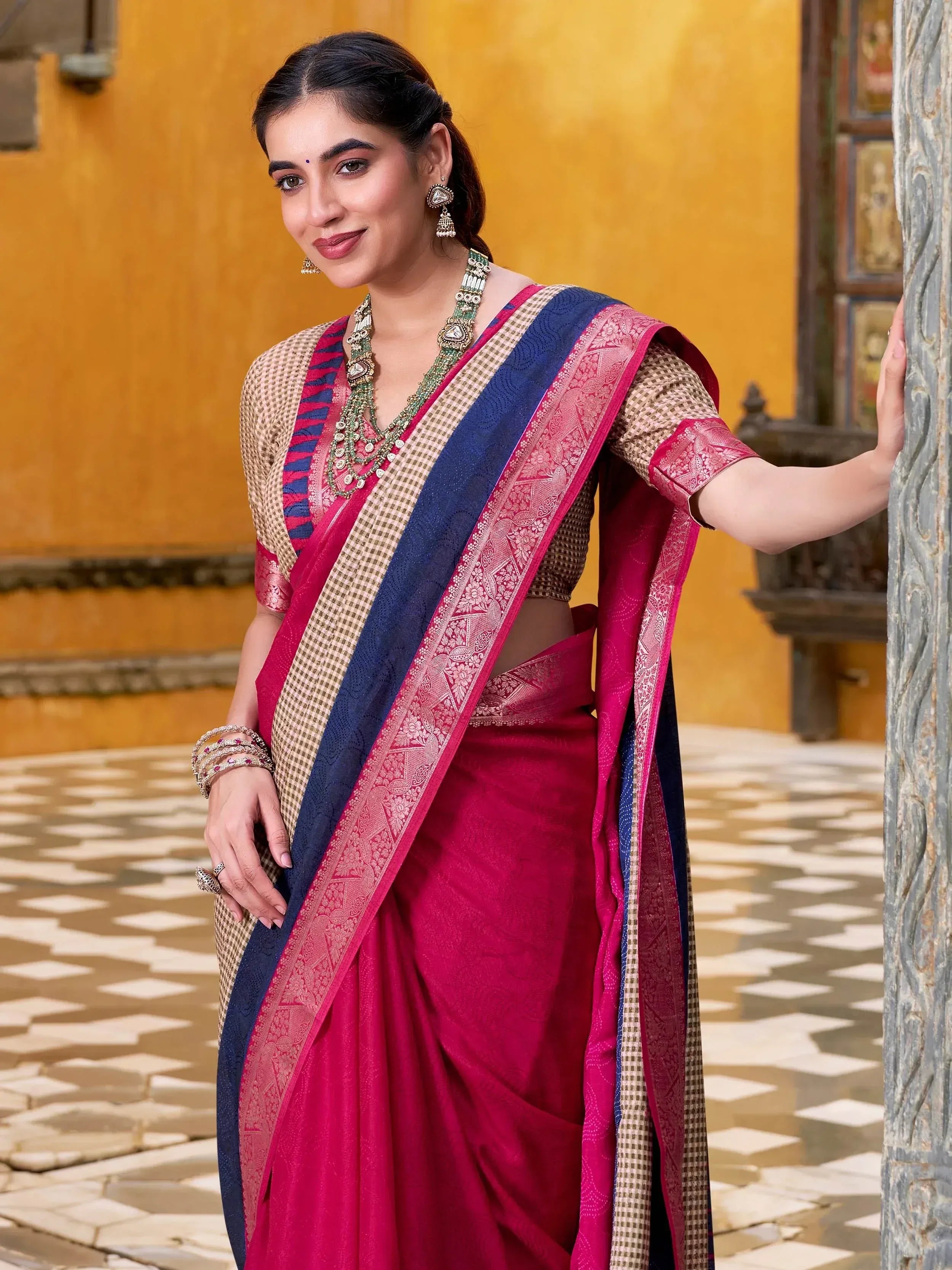 Woman in vibrant pink and blue designer saree with checkered blouse, traditional Indian ethnic wear