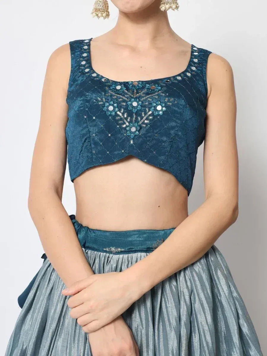 Teal embroidered crop top with mirror work, paired with silver pleated skirt for ethnic wear