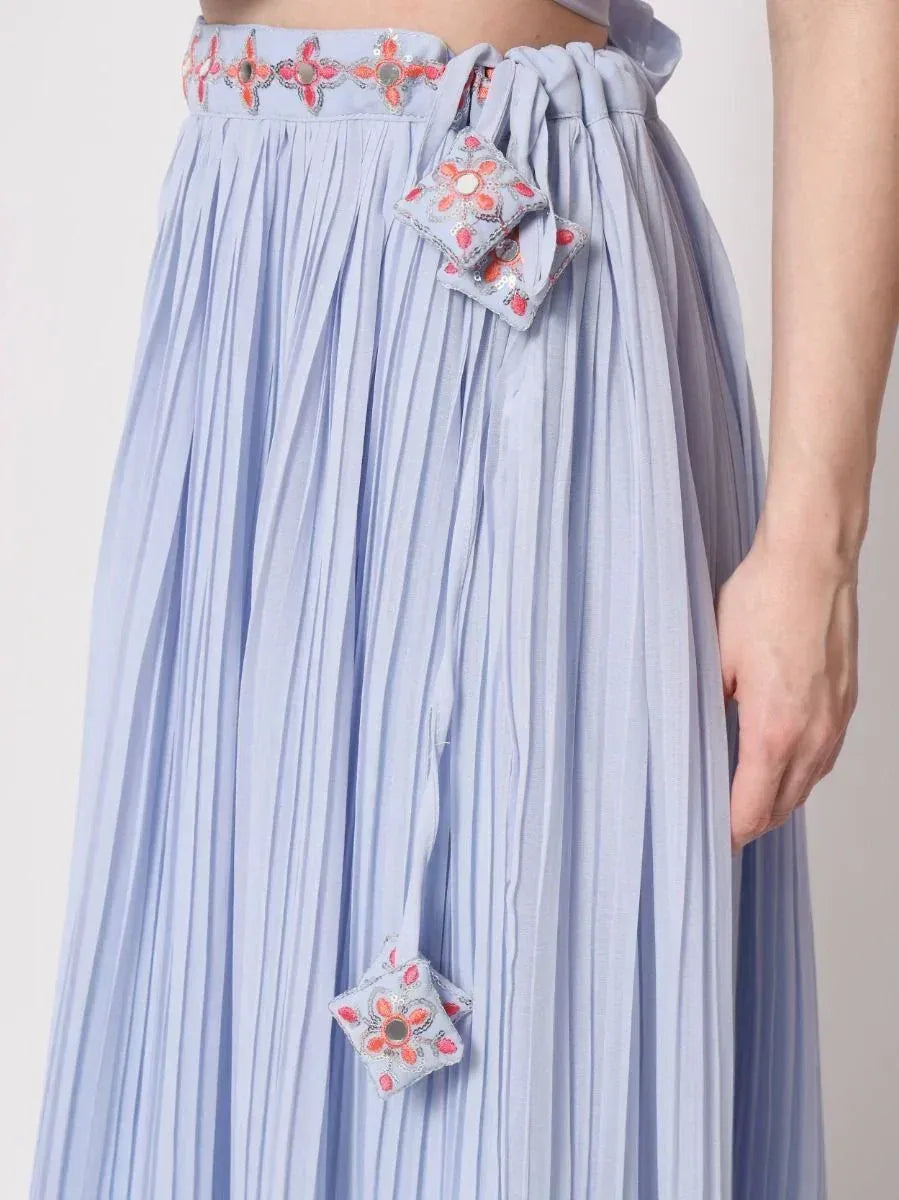 Light blue pleated ethnic skirt with floral embroidery and decorative tassels, perfect for Indian wear.