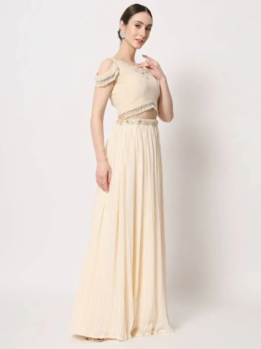 Cream ethnic gown with fringed crop top and pleated skirt, perfect for Indian occasions