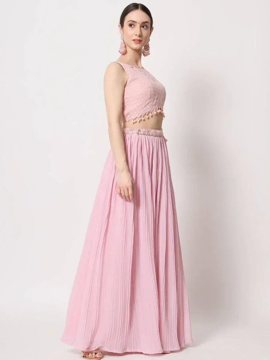 Pink ethnic lehenga choli with pleated skirt and embroidered crop top, perfect for Indian weddings or festive occasions.