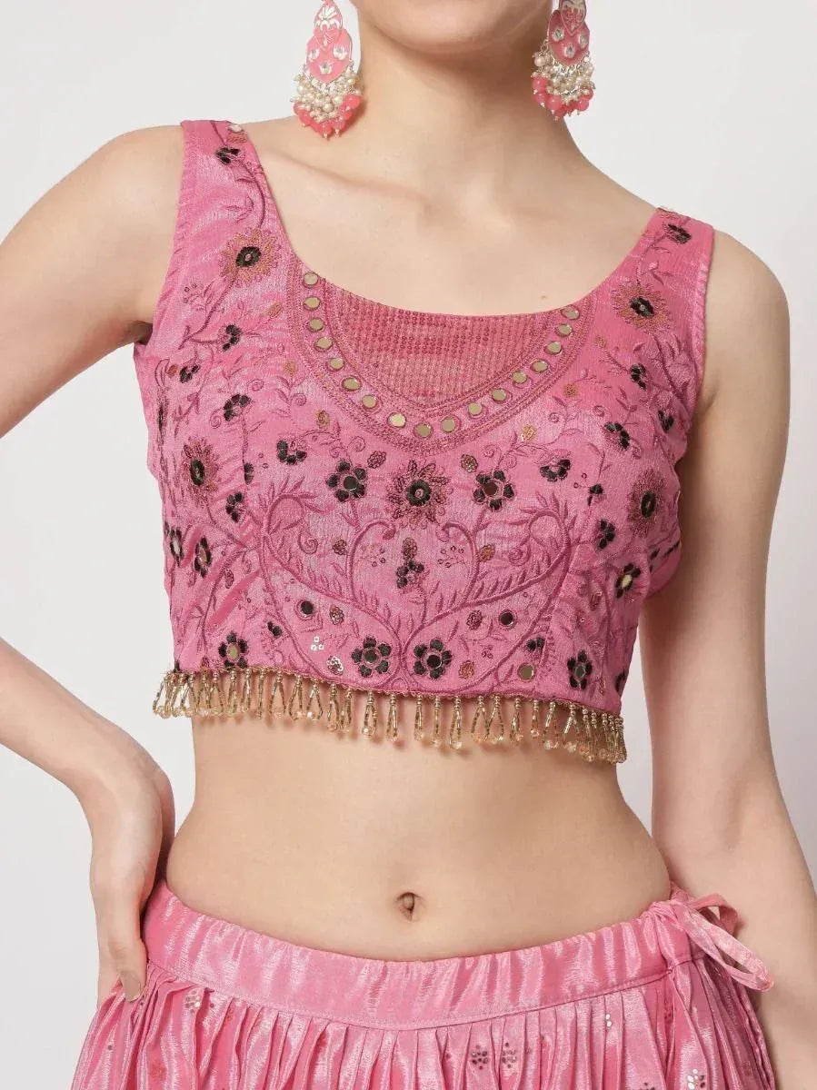 Pink embroidered crop top with floral motifs and gold tassels, paired with matching skirt for ethnic wear