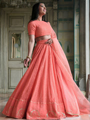 Woman wearing a coral pink traditional outfit with a matching dupatta in an indoor setting.