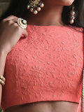 Close-up of a person wearing a coral pink blouse with floral patterns and jewelry.