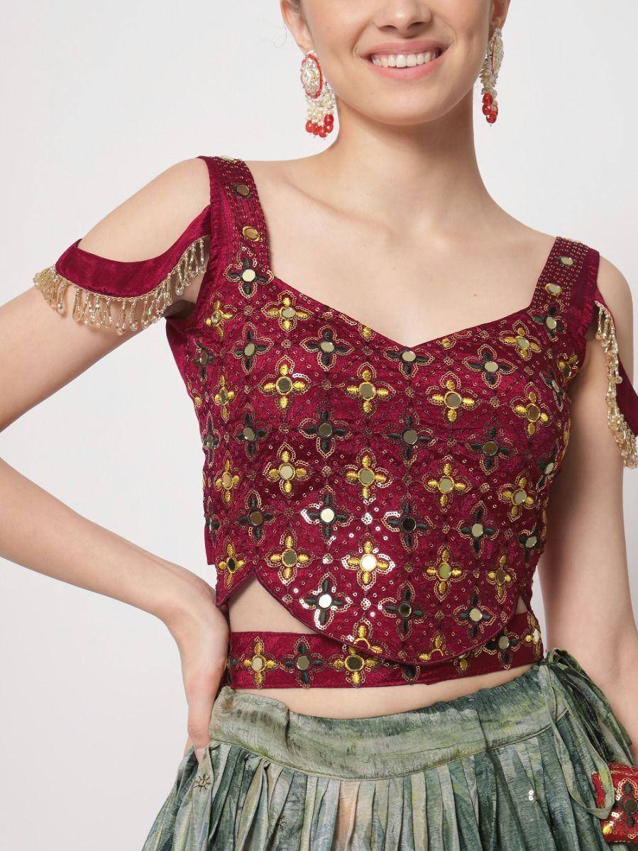 Maroon embroidered cold shoulder blouse with mirror work, paired with green lehenga for Indian ethnic wear