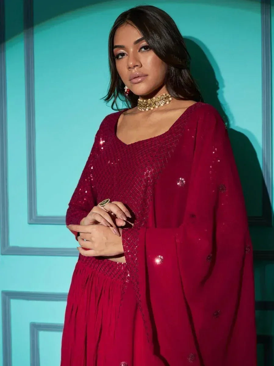 Woman in maroon sequin ethnic gown with gold jewelry, perfect for Indian festive occasions