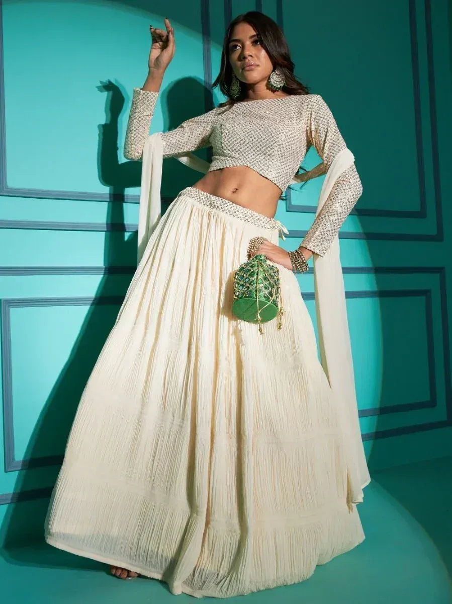 Cream embroidered lehenga choli with pleated skirt, green potli bag, and statement earrings for Indian ethnic wear