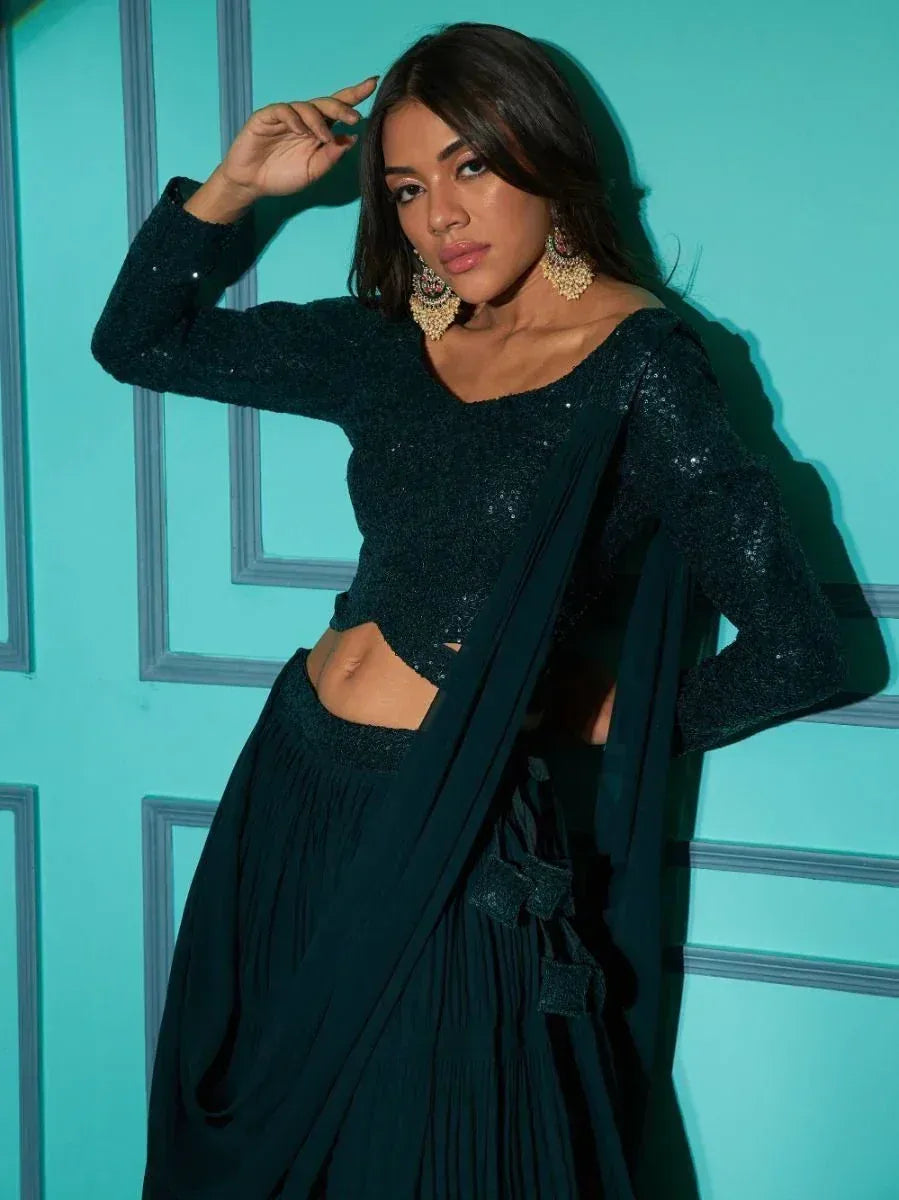 Sparkly dark green lehenga choli with long sleeves and pleated skirt, styled with statement earrings