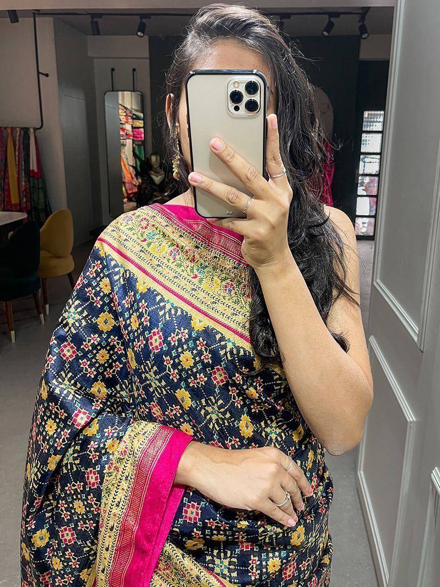 Woman wearing vibrant floral saree with pink border, capturing mirror selfie in boutique