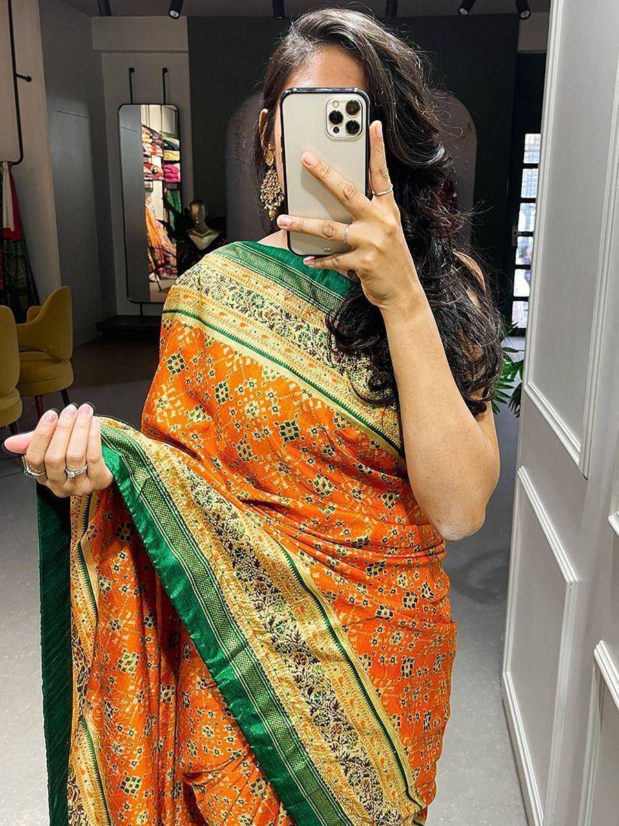 Orange and green printed saree with intricate border design, perfect for ethnic occasions.
