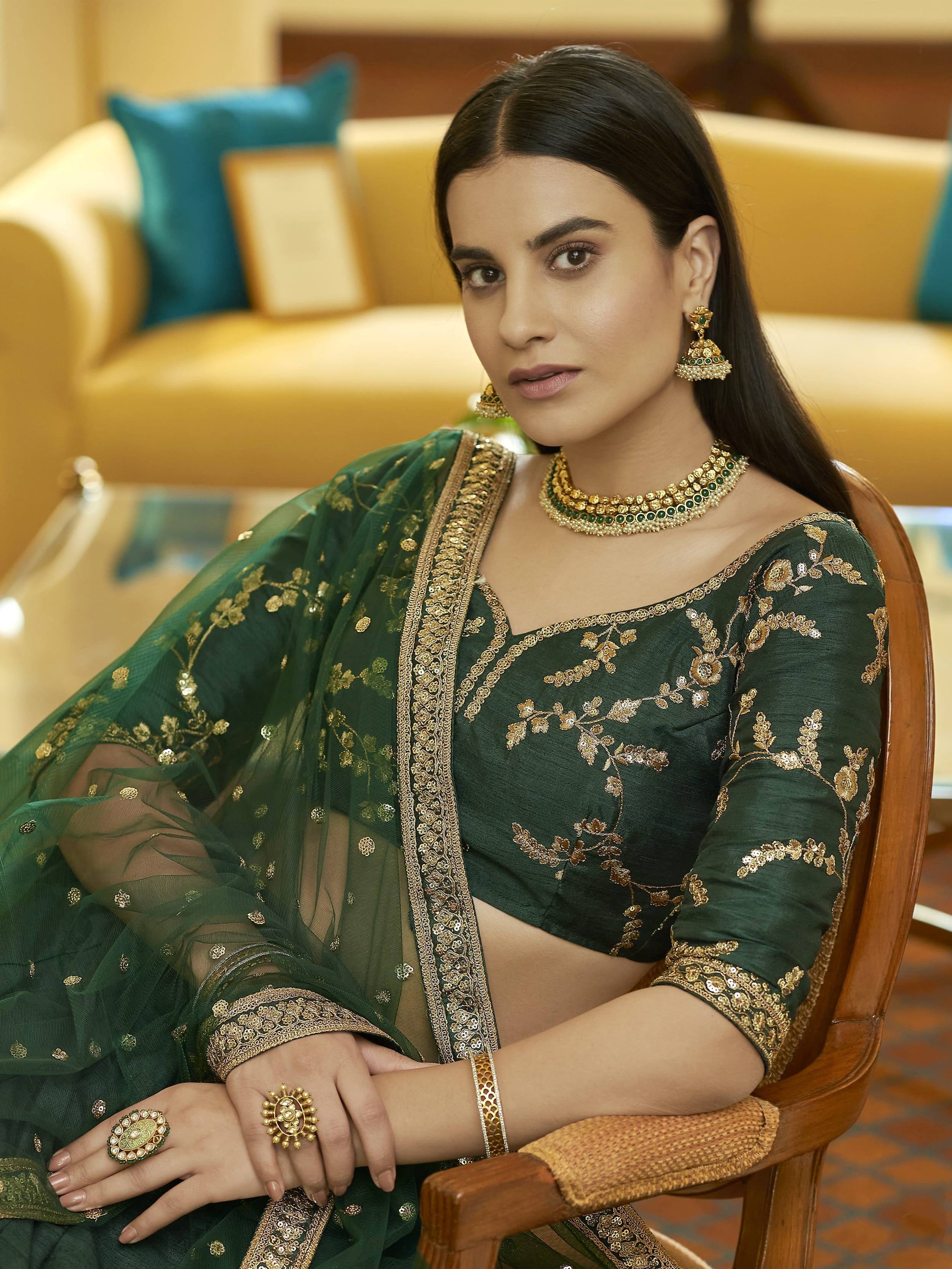 Elegant green embroidered lehenga choli with gold detailing, paired with traditional jewelry for festive occasions.